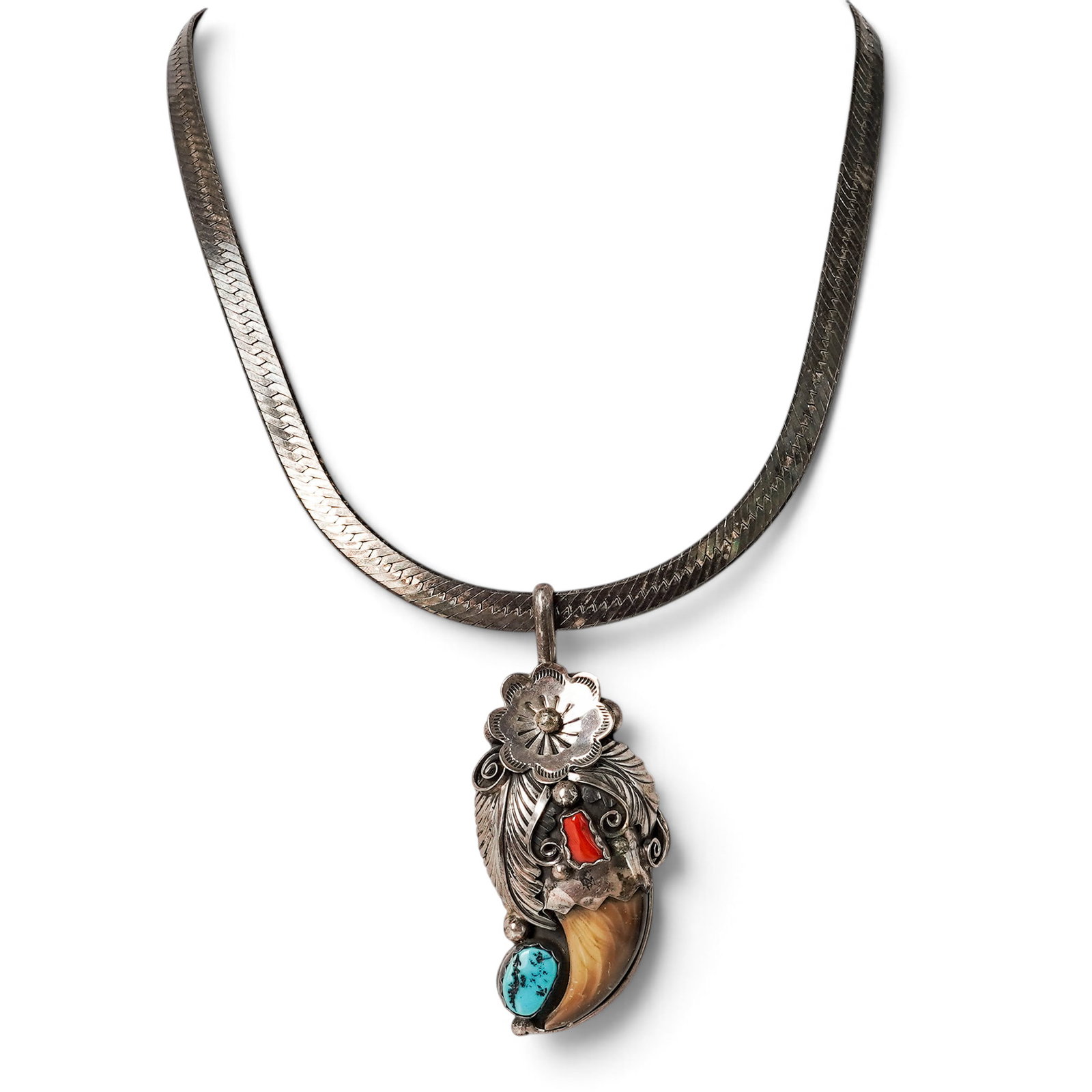 A Navajo Sterling Silver, Turquoise, Coral, And Claw Pendant Necklace: A Navajo Sterling Silver, Turquoise, Coral, And Claw Pendant Necklace Late 20th century Stamped: Sterling / 925. A necklace with a pendant featuring a polished claw accented by bezel-set turquoise and