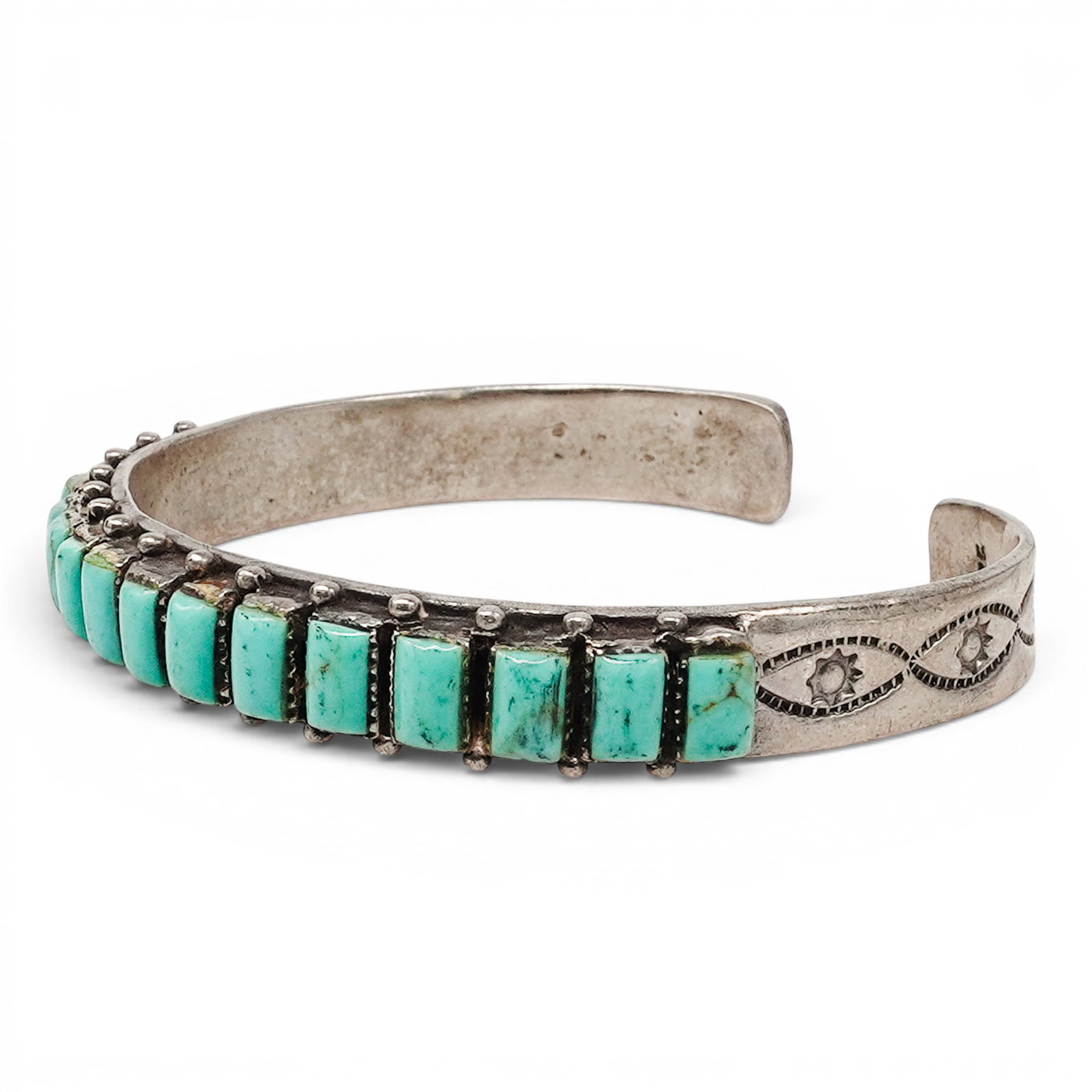 A Navajo Sterling Silver And Turquoise Channel Set Cuff Bracelet: A Navajo Sterling Silver And Turquoise Channel Set Cuff Bracelet Late 20th century Stamped: .925. A narrow cuff bracelet with a continuous row of rectangular channel set turquoise stones accented by s