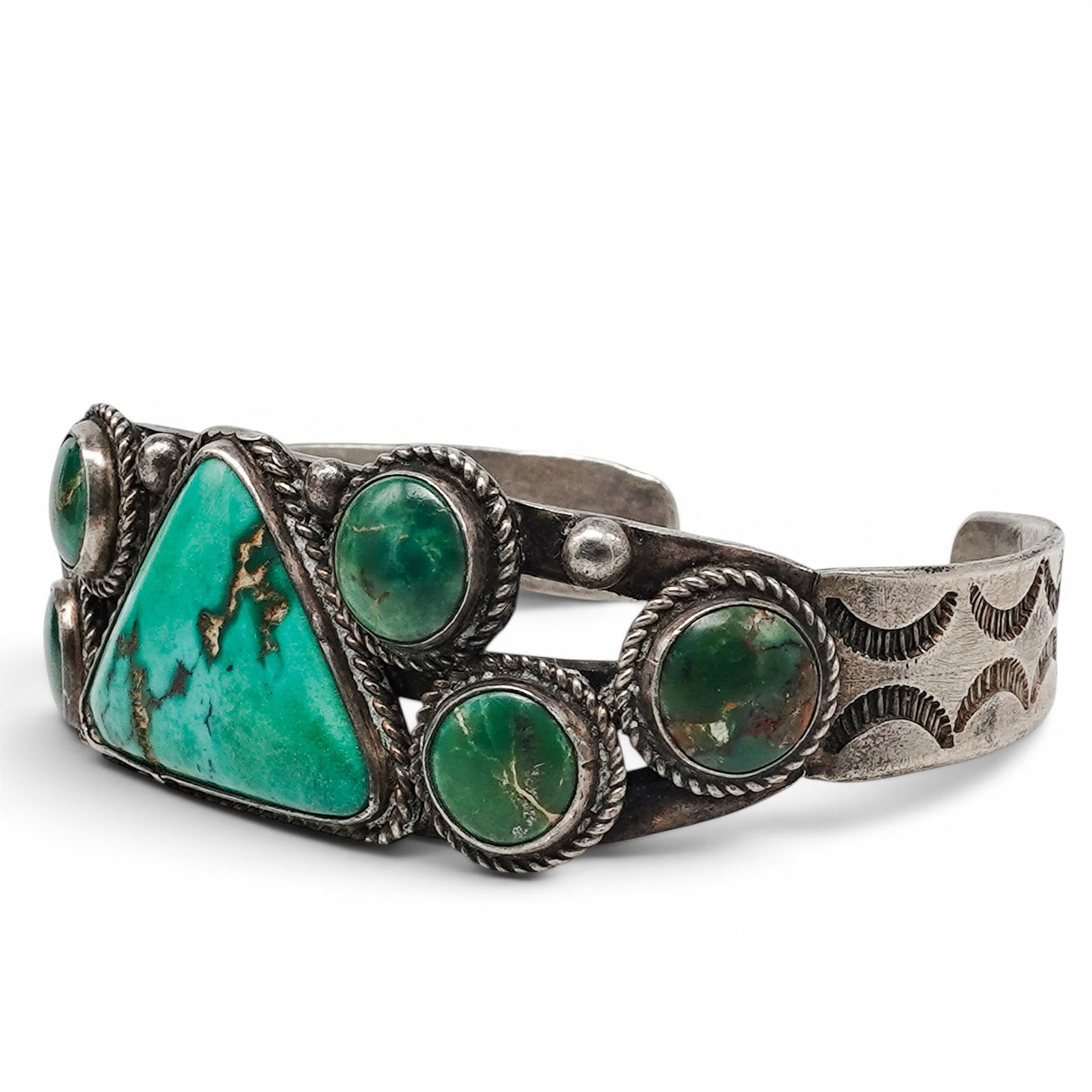 A Navajo Sterling Silver And Turquoise Seven Stone Cuff Bracelet: A Navajo Sterling Silver And Turquoise Seven Stone Cuff Bracelet Late 20th century Unmarked. Tested sterling silver. A cuff bracelet with a central triangular turquoise stone flanked by six oval green