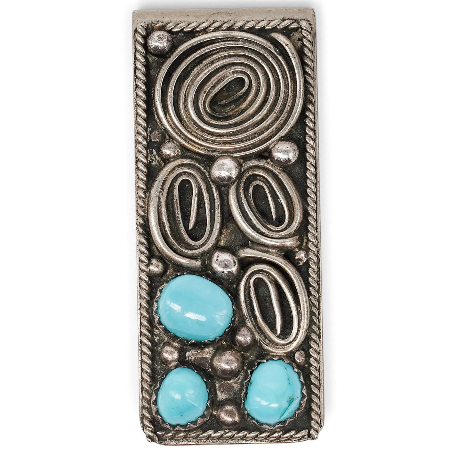 A Navajo Sterling Silver And Turquoise Wirework Money Clip: A Navajo Sterling Silver And Turquoise Wirework Money Clip Late 20th century Unmarked. Tested sterling silver. A rectangular silver money clip with three bezel-set turquoise cabochons, heavy spiral wi