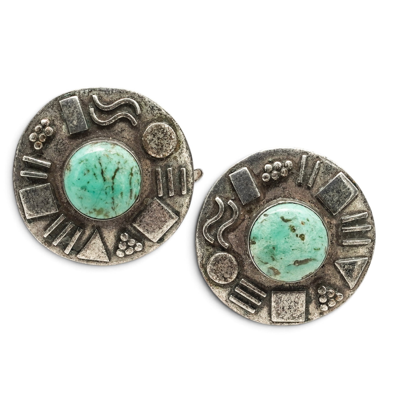 A Pair Of Navajo Sterling Silver And Turquoise Post Earrings: A Pair Of Navajo Sterling Silver And Turquoise Post Earrings Late 20th century Stamped: 925. Each circular earring centered by a bezel-set turquoise cabochon with applied geometric silver accents and 