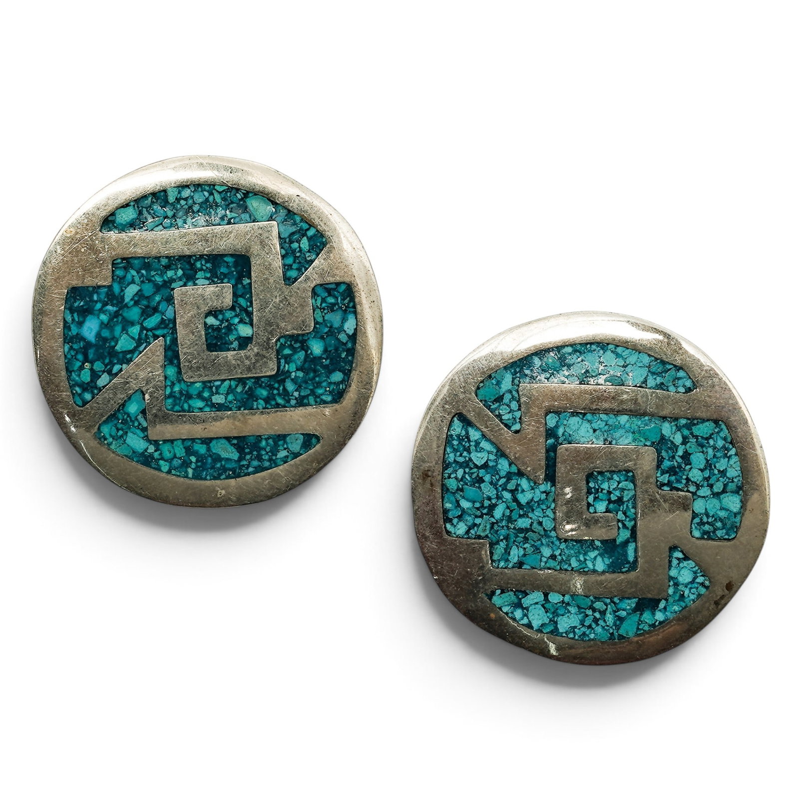 A Pair Of Mexican Sterling Silver And Turquoise Chip Inlay Clip Earrings: A Pair Of Mexican Sterling Silver And Turquoise Chip Inlay Clip Earrings Late 20th century Marked: Alpaca / Mexico. Each circular earring with turquoise chip inlay surrounding a central geometric moti