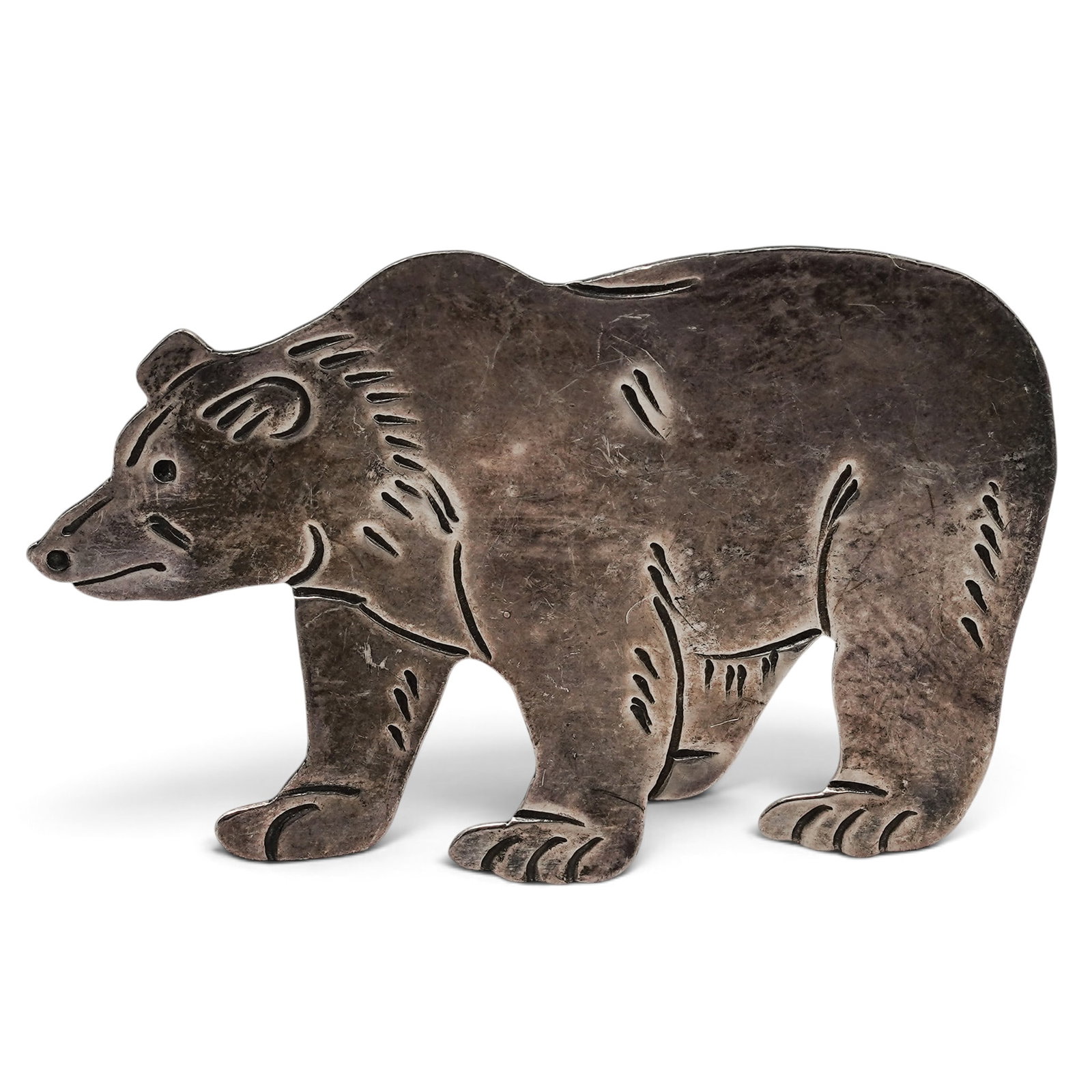 A Navajo Sterling Silver Bear Brooch: A Navajo sterling silver bear brooch Late 20th century Stamped: Sterling. A cutout bear-form brooch with engraved facial features, fur details, and articulated stance rendered in sheet silver construc