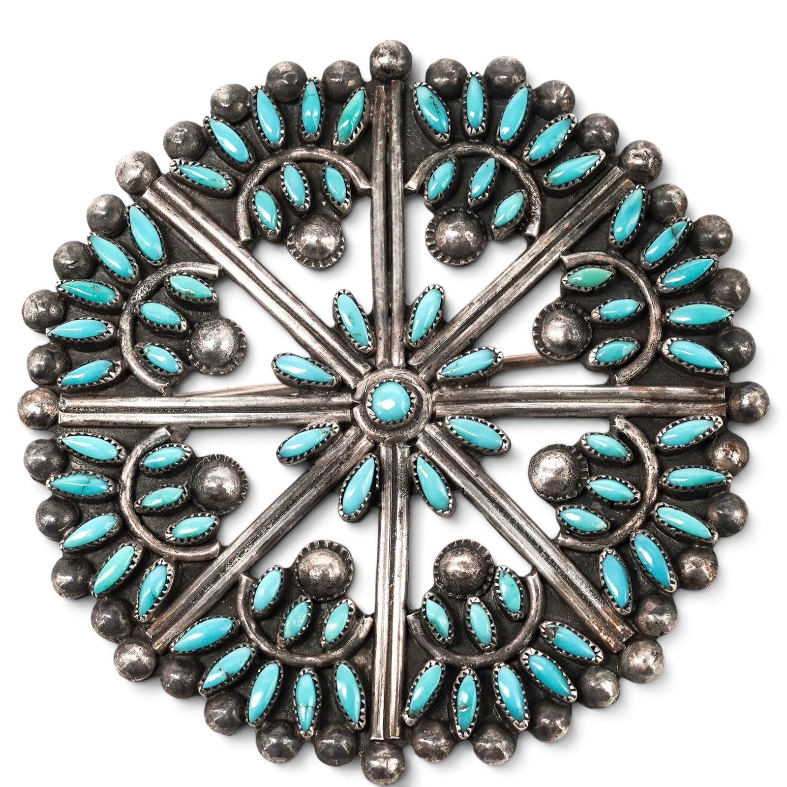 A Zuni Sterling Silver And Turquoise Needlepoint Brooch: A Zuni sterling silver and turquoise needlepoint brooch Late 20th century Unmarked. Tested sterling silver. A circular brooch with radial arrangement of turquoise needlepoint stones in serrated bezels