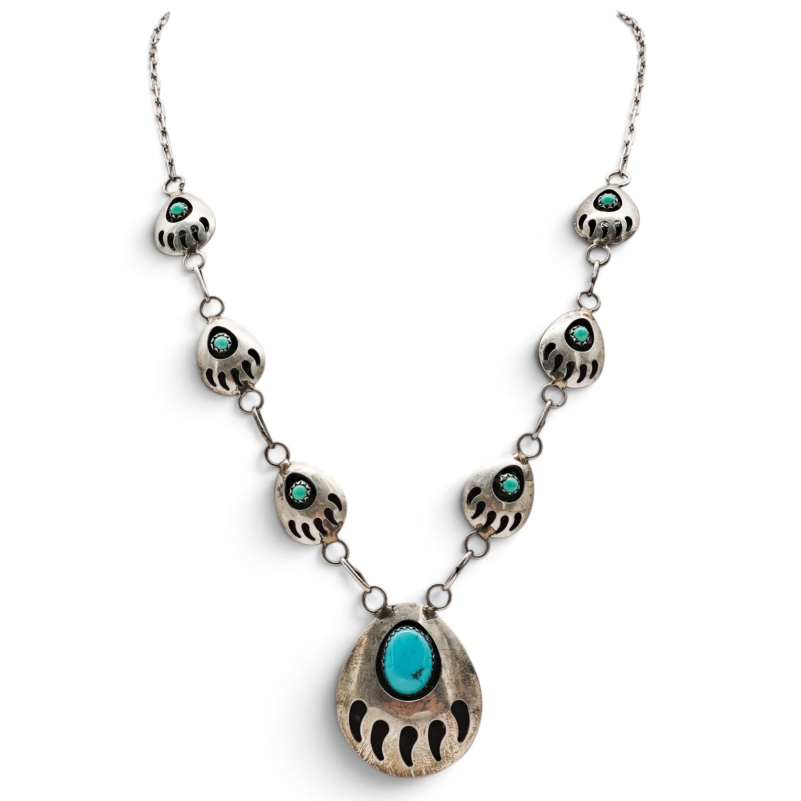 A Navajo Sterling Silver And Turquoise Bear Paw Link Necklace: A Navajo sterling silver and turquoise bear paw link necklace Late 20th century Unmarked. Tested sterling silver. A necklace with eight bear paw-form links, each centered by a bezel-set turquoise cabo