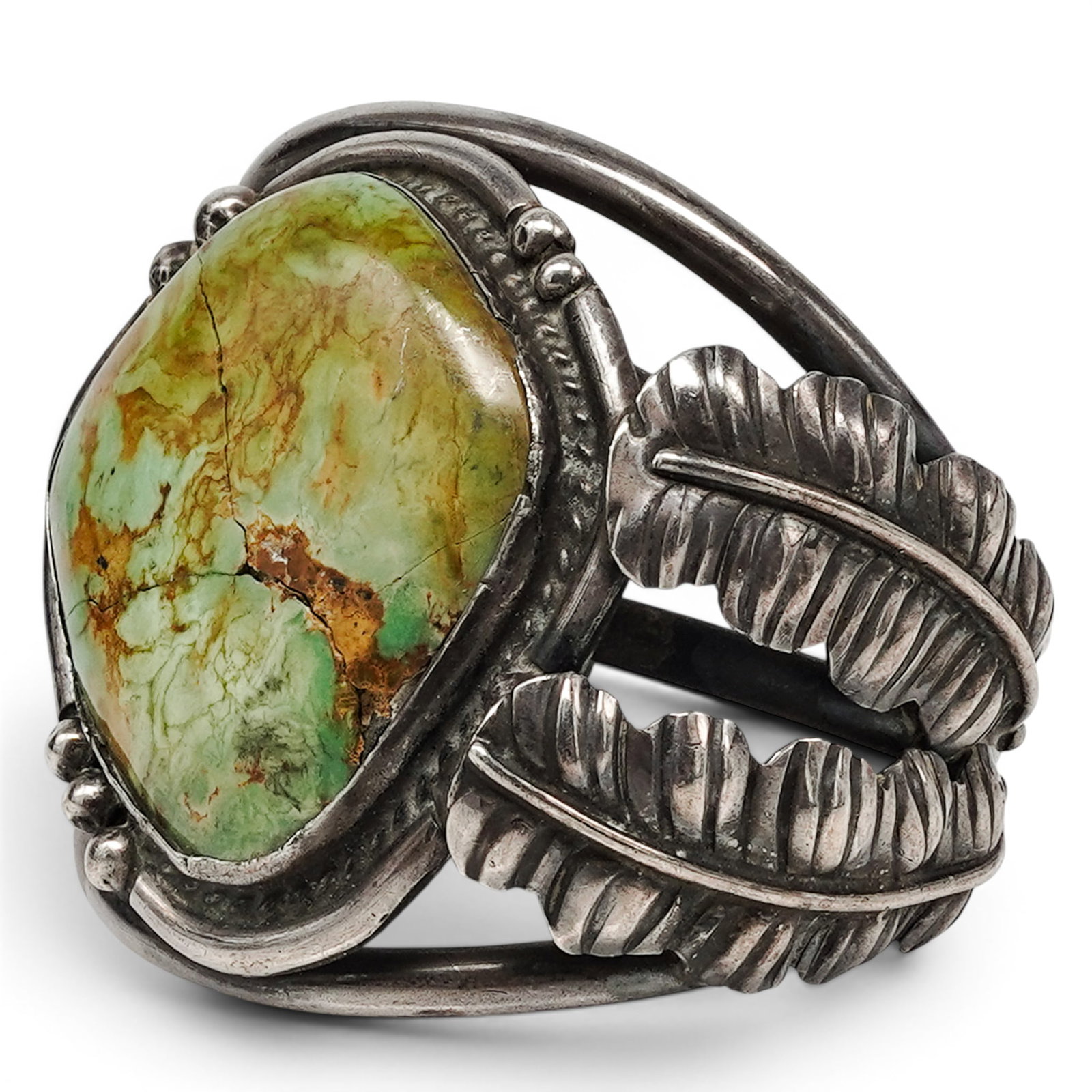A Navajo Sterling Silver And Green Turquoise Cuff Bracelet: A Navajo sterling silver and green turquoise cuff bracelet Late 20th century Unmarked. Tested sterling silver. A heavy cuff bracelet with a large asymmetrical green turquoise cabochon in a rope wire b
