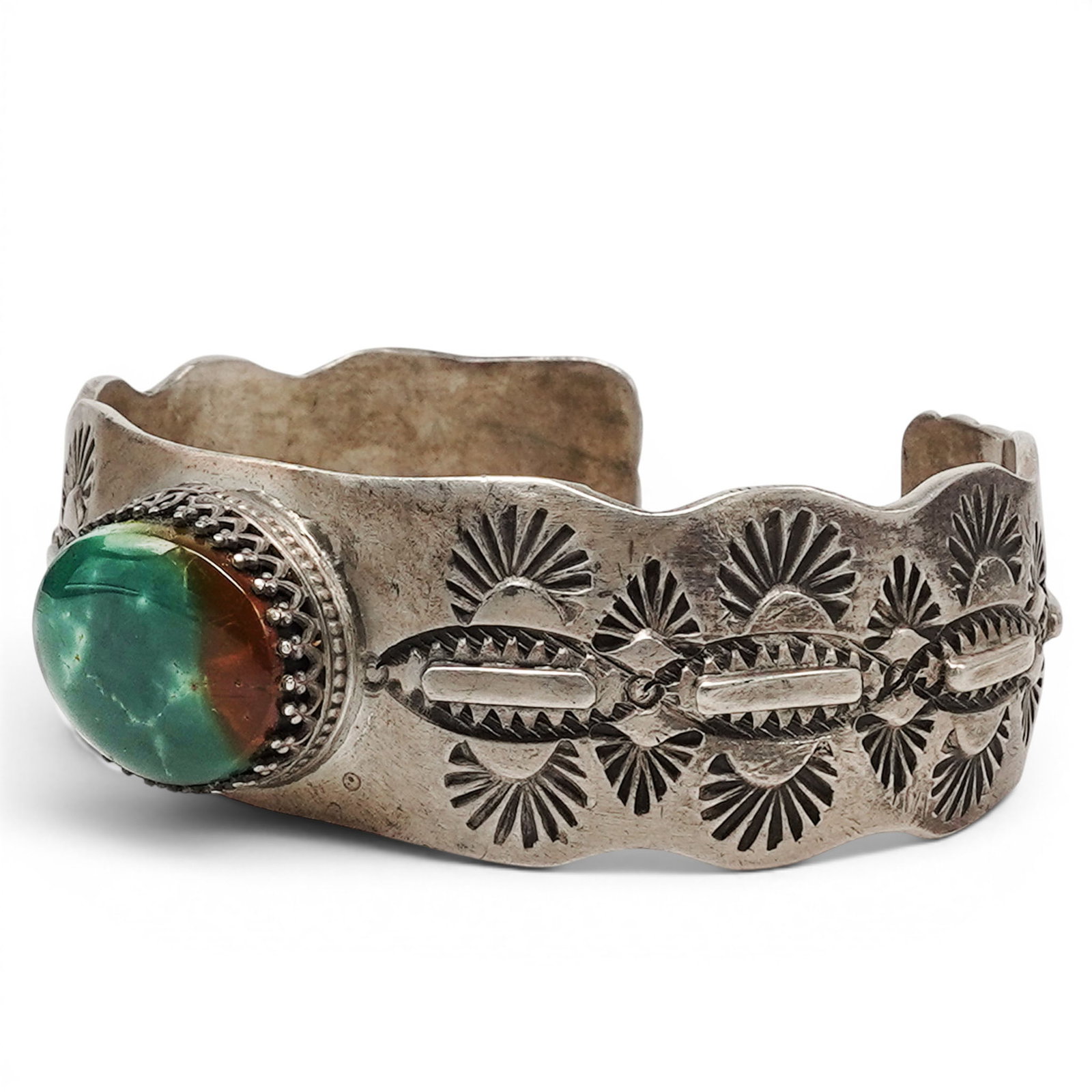 A Navajo Sterling Silver And Green Stone Cuff Bracelet: A Navajo sterling silver and green stone cuff bracelet Late 20th century Stamped: A.L. / Sterling / Pictographic hallmark. A cuff bracelet with an oval green stone cabochon in a rope wire bezel, flank