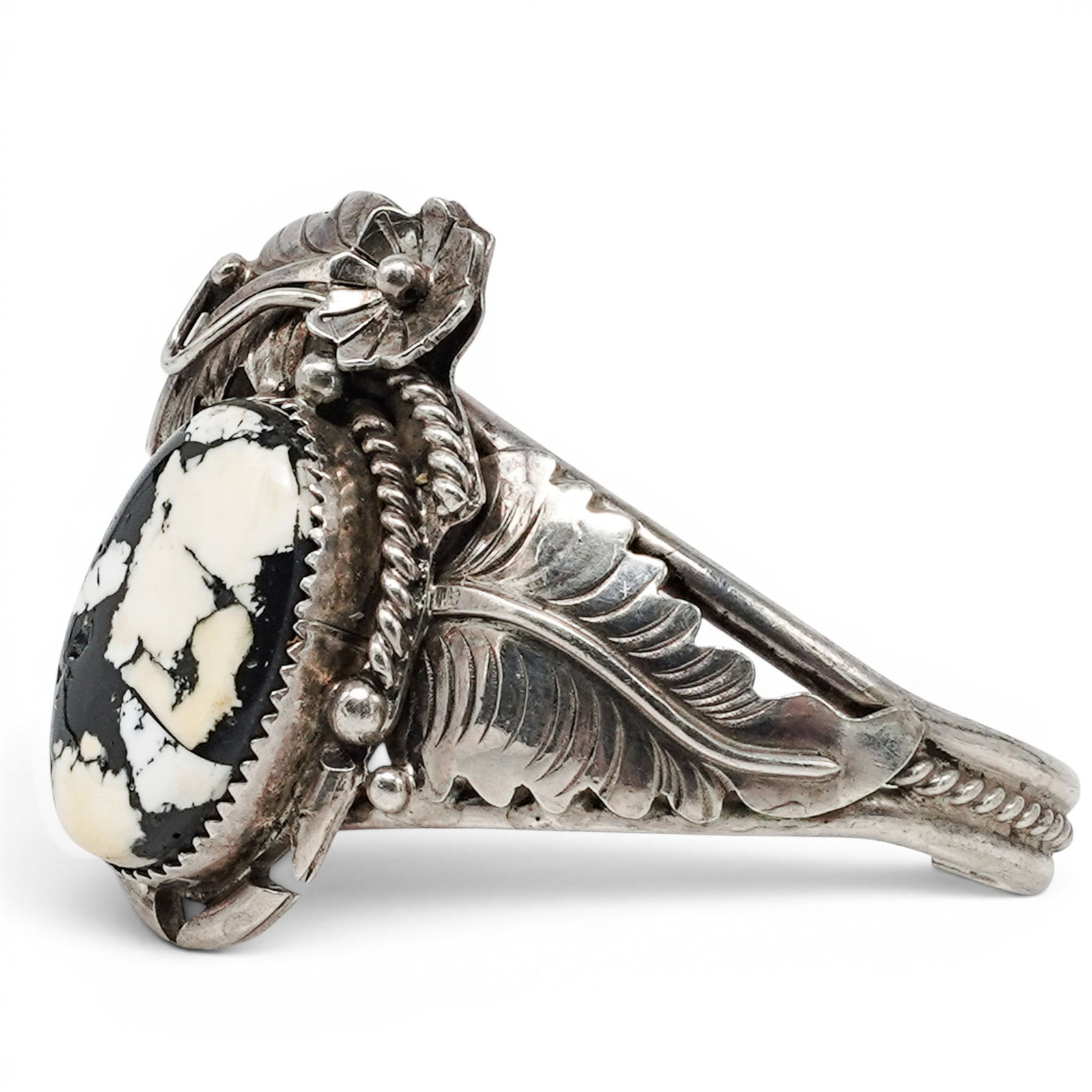 A Glen Willie Navajo Sterling Silver And White Buffalo Stone Cuff Bracelet: A Glen Willie Navajo sterling silver and white buffalo stone cuff bracelet Late 20th century Stamped: G.W. / Sterling A cuff bracelet with a large oval black and white buffalo stone cabochon in a serr