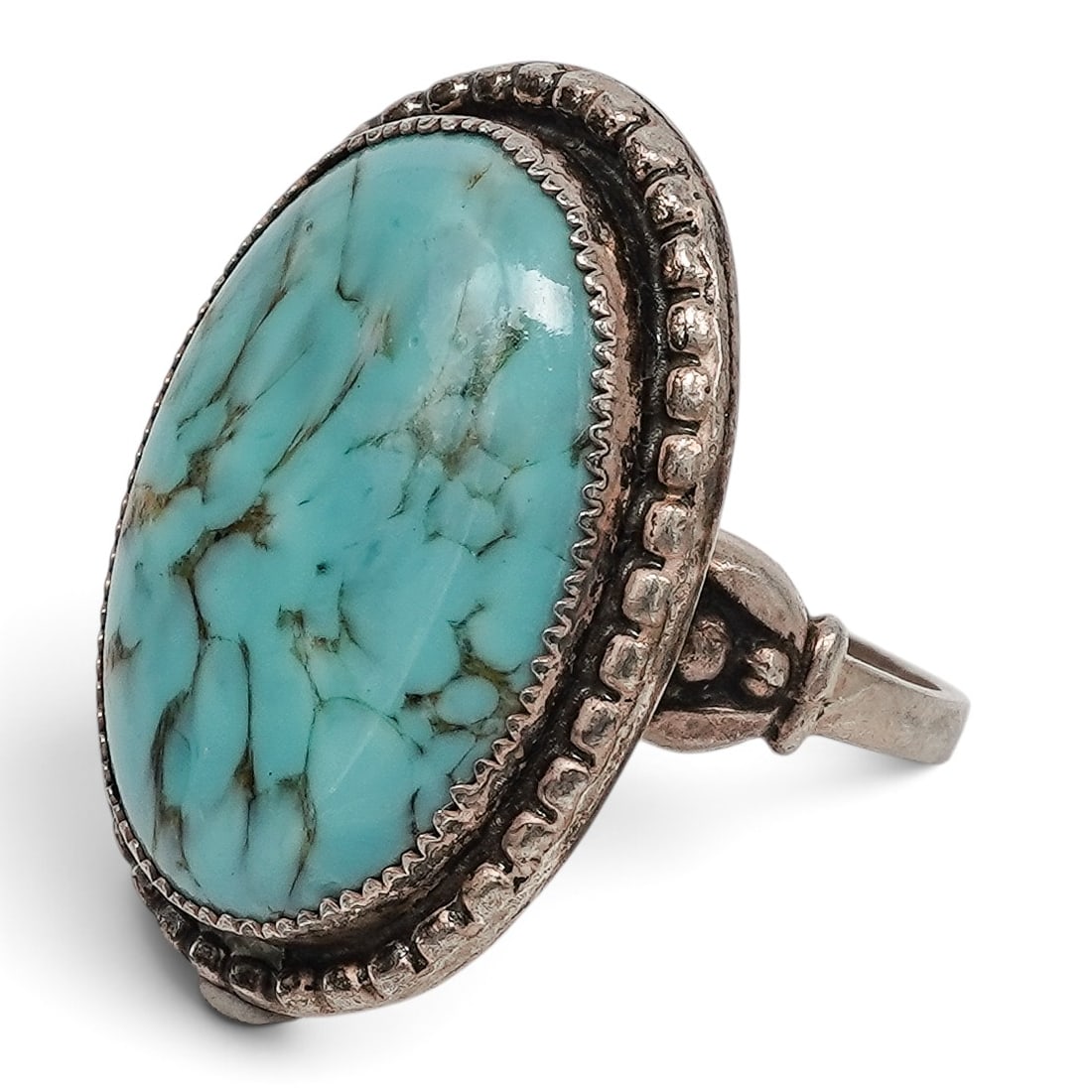 A Navajo Sterling Silver And Turquoise Beaded Border Ring: A Navajo sterling silver and turquoise beaded border ring Late 20th century Stamped: D, unidentified hallmark / Sterling. A ring set with a large oval turquoise cabochon with spiderweb matrix in a ser