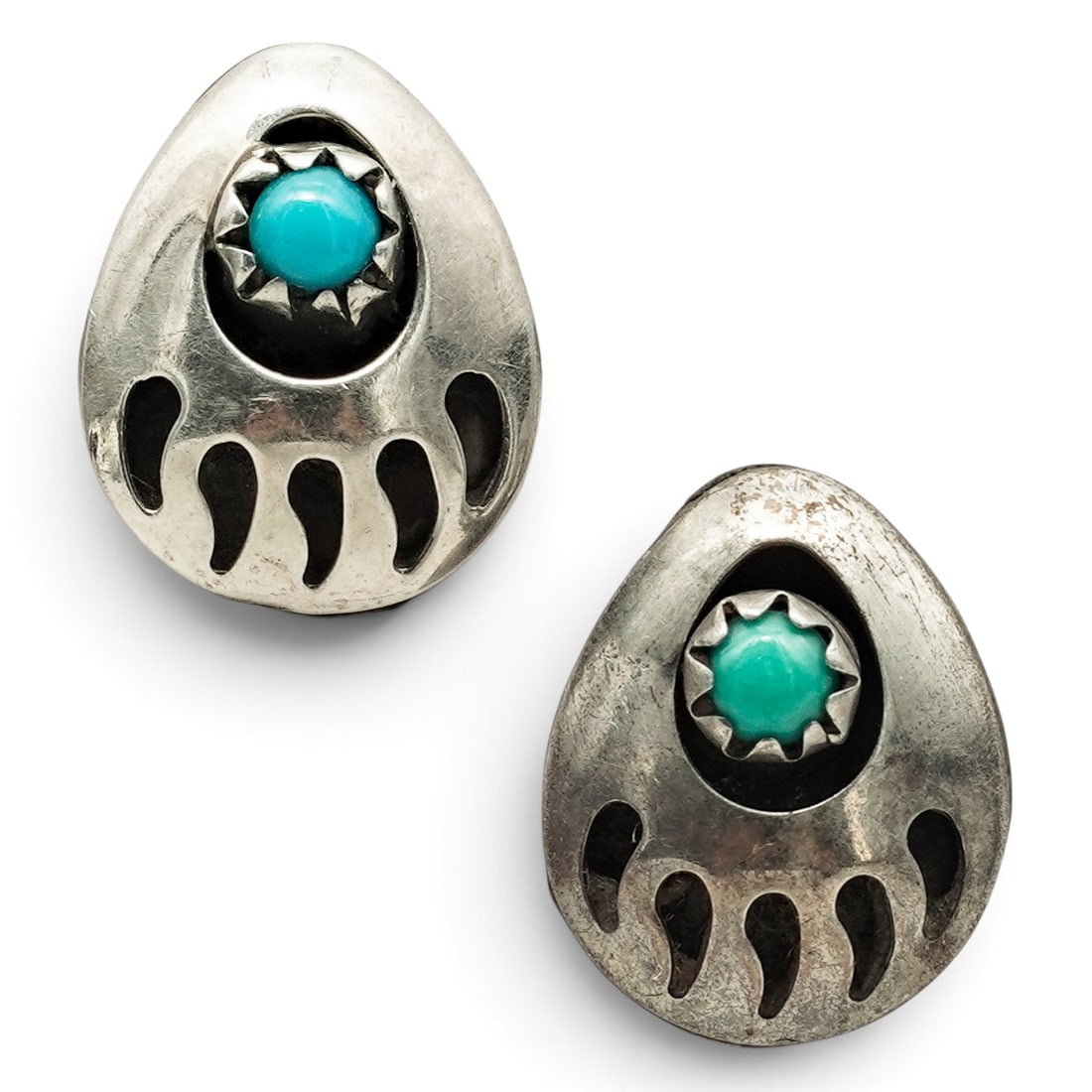 A Pair Of Navajo Sterling Silver And Turquoise Bear Paw Post Earrings: A pair of Navajo sterling silver and turquoise bear paw post earrings Late 20th century Unmarked. Tested sterling silver. Each in the form of a stylized bear paw centered by a bezel-set turquoise cabo
