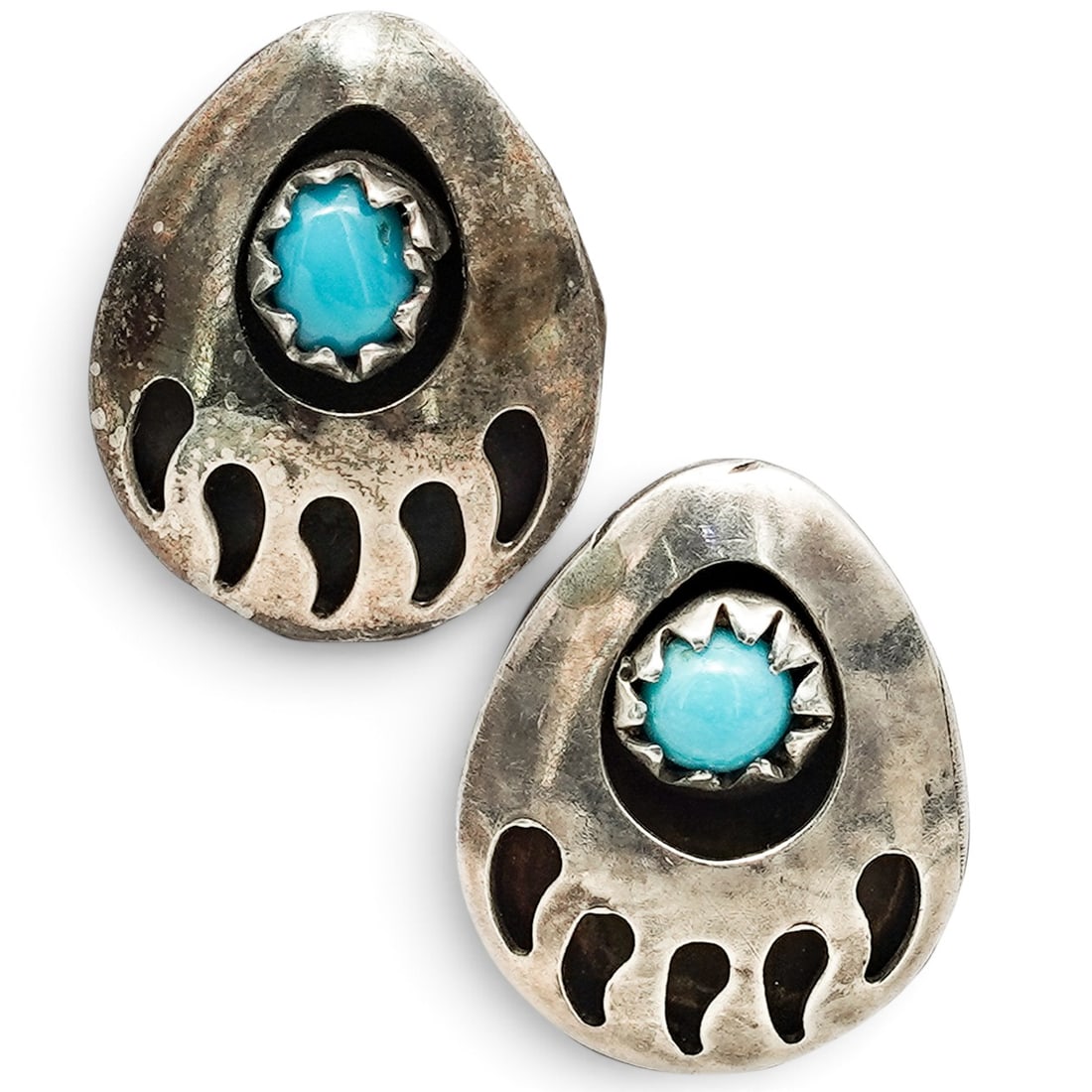 A Pair Of Navajo Sterling Silver And Turquoise Bear Paw Earrings: A pair of Navajo sterling silver and turquoise bear paw earrings Late 20th century Unmarked Tests for sterling. Each bear paw-form post earring is pierced with claw motifs and set with a small round t