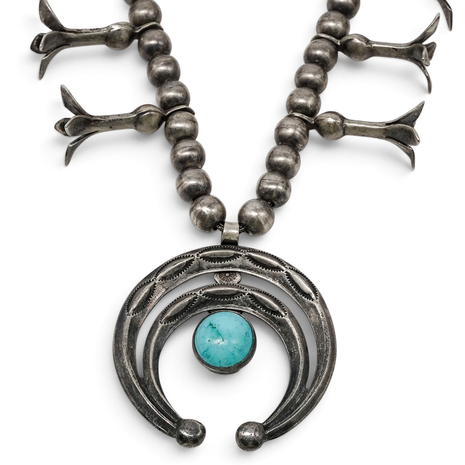 A Navajo Sterling Silver And Turquoise Squash Bottom Necklace: A Navajo sterling silver and turquoise squash bottom necklace Late 20th century Unmarked. Tested sterling silver. A necklace composed of double strands of silver beads with ten naja-form squash blosso
