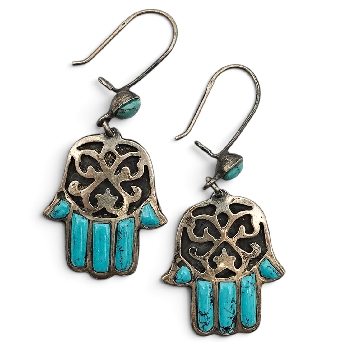 A Pair Of Sterling Silver And Turquoise Hamsa Dangle Earrings: A pair of sterling silver and turquoise Hamsa dangle earrings Late 20th century Unmarked. Tested sterling silver. Each in the form of a Hamsa hand with turquoise inlay accents and openwork scroll moti