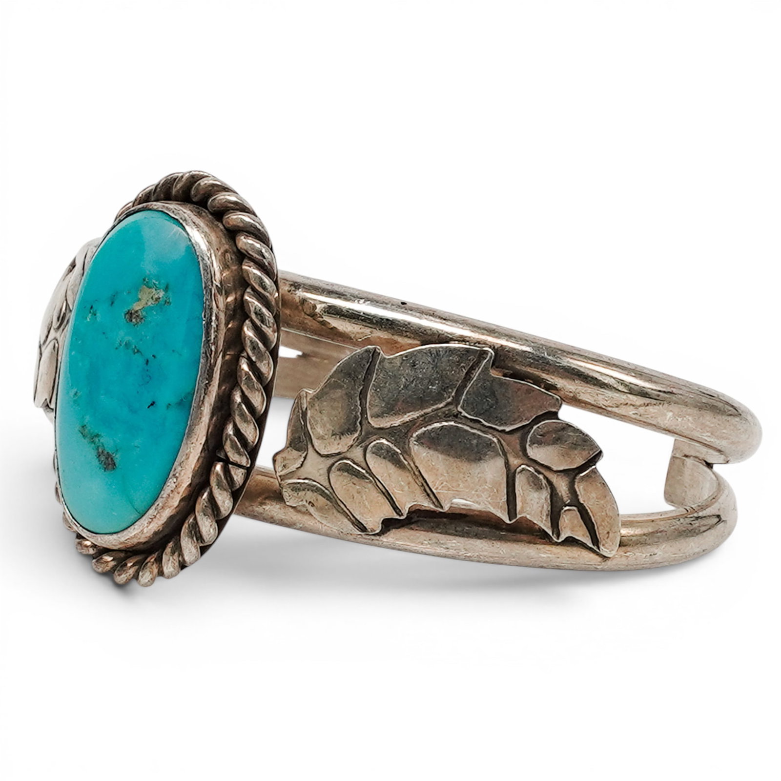 A Navajo Sterling Silver And Turquoise Cuff Bracelet: A Navajo sterling silver and turquoise cuff bracelet Late 20th century Unmarked. Tested sterling silver. A cuff bracelet with a central oval bezel set turquoise cabochon framed by twisted wire, with s