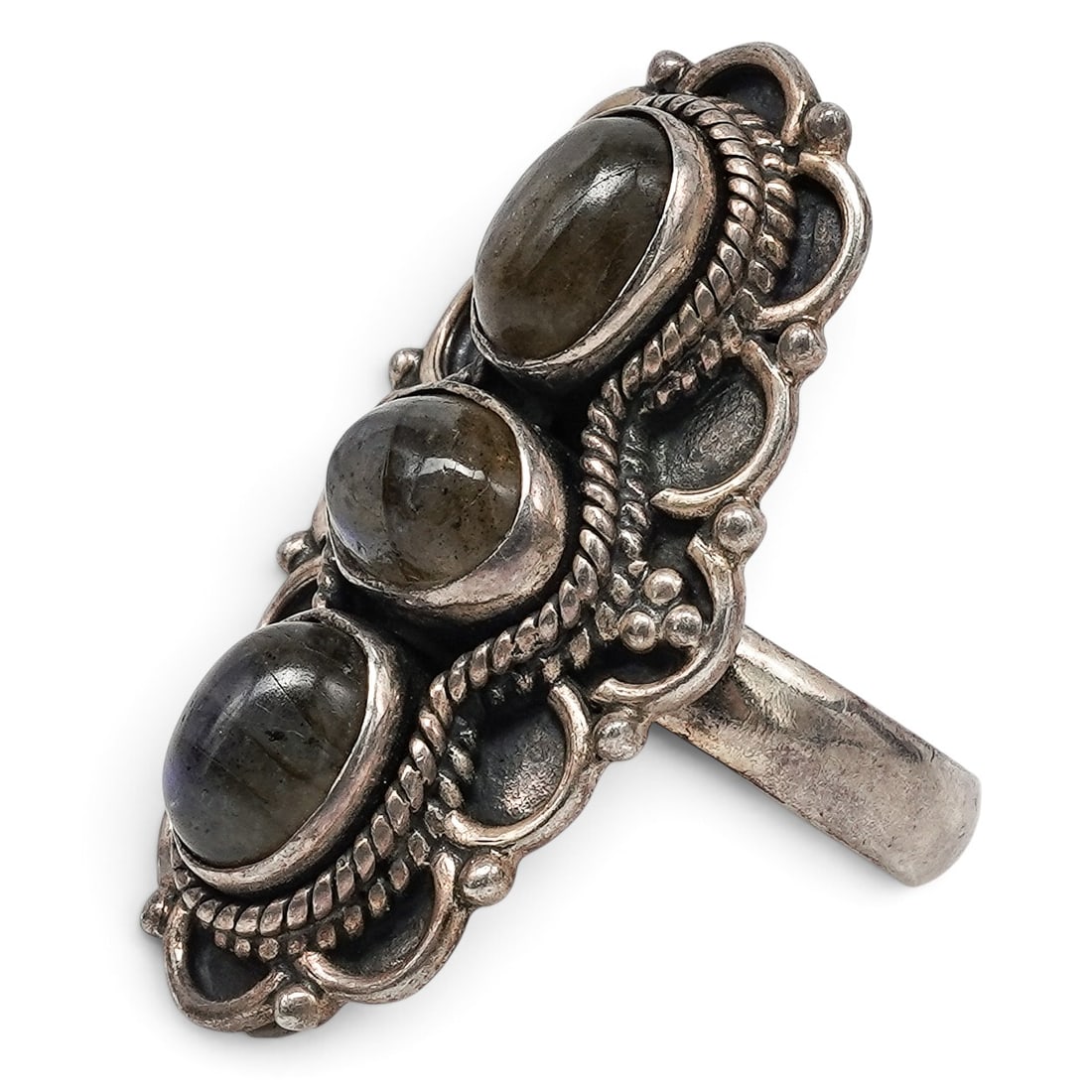 A Navajo Sterling Silver And Labradorite Three-stone Ring: A Navajo sterling silver and labradorite three-stone ring Late 20th century Stamped: .925. An elongated ring set with three oval labradorite cabochons, with rope wire accents and openwork scrollwork s