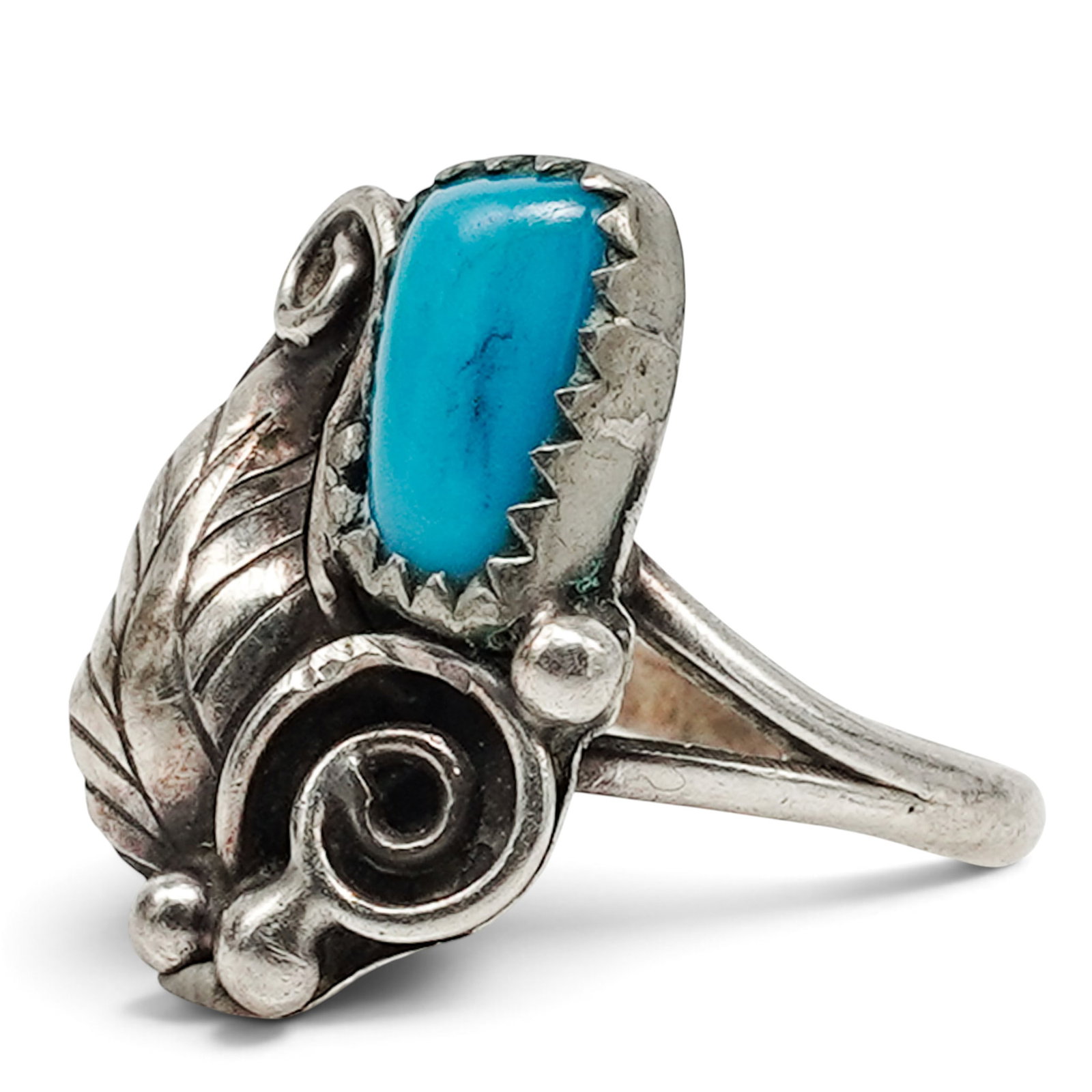 A Navajo Sterling Silver And Turquoise Leaf Scrollwork Ring: A Navajo sterling silver and turquoise leaf scrollwork ring Late 20th century Unmarked. Tested sterling silver. A ring set with a small oval turquoise cabochon in a serrated bezel, with applied leaf a