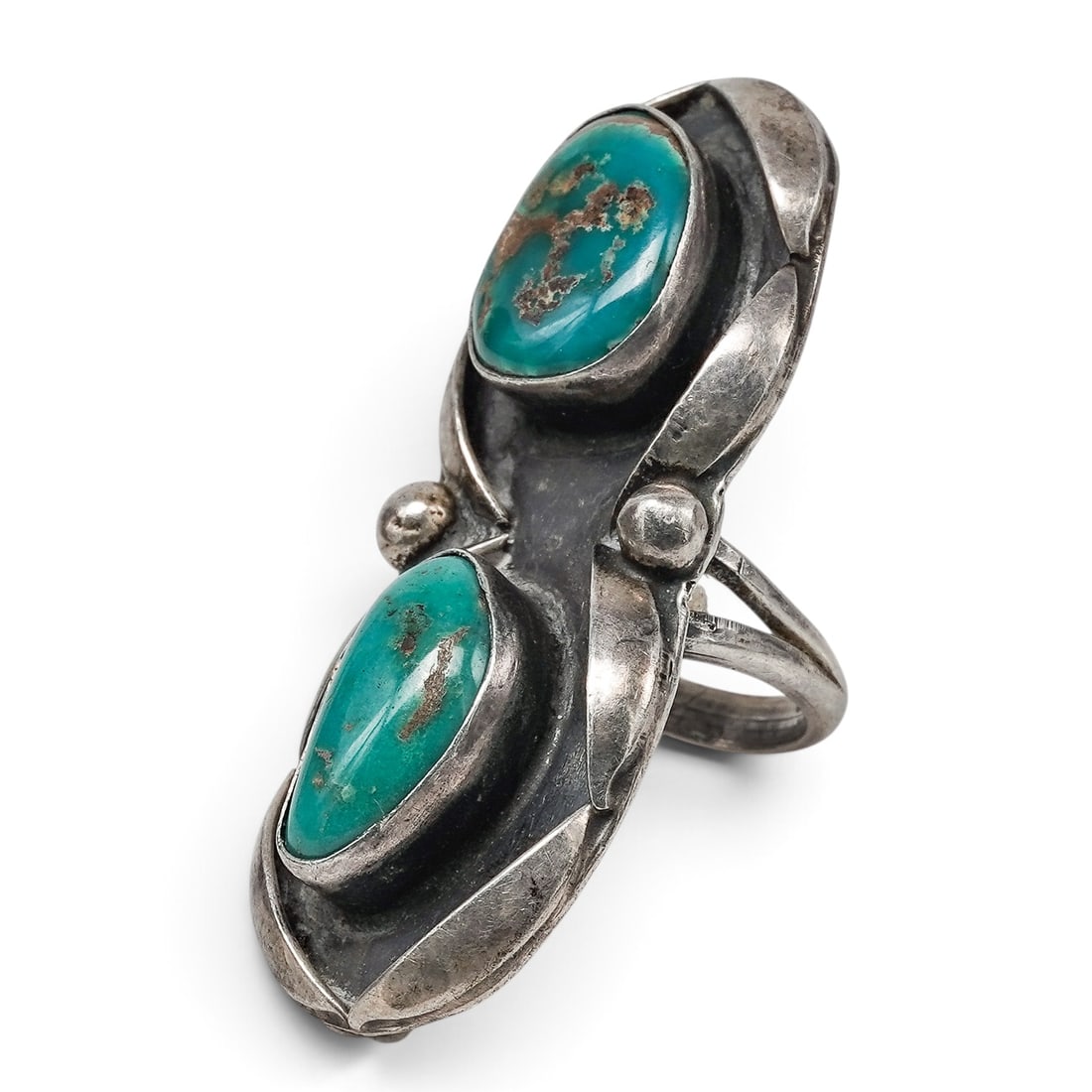 A Navajo Sterling Silver And Turquoise Two-stone Shadowbox Ring: A Navajo sterling silver and turquoise two-stone shadowbox ring Late 20th century Unmarked. Tested sterling silver. A large ring with two oval turquoise cabochons in shadowbox settings, joined by scul