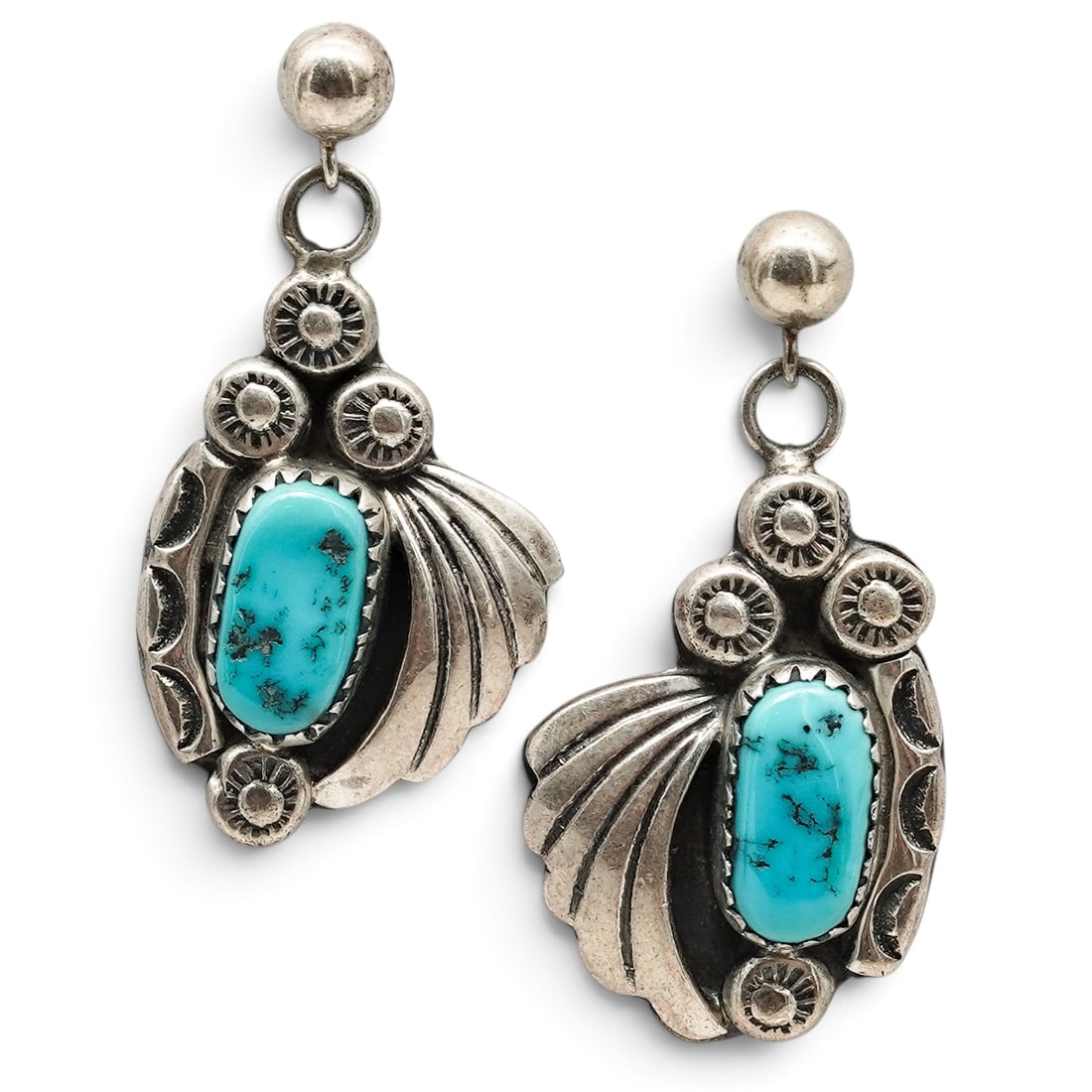 A Pair Of Navajo Sterling Silver And Turquoise Leaf Dangle Post Earrings: A pair of Navajo sterling silver and turquoise leaf dangle post earrings Late 20th century Unmarked. Tested sterling silver. Each with an oval bezel-set turquoise cabochon accented by applied leaf mot