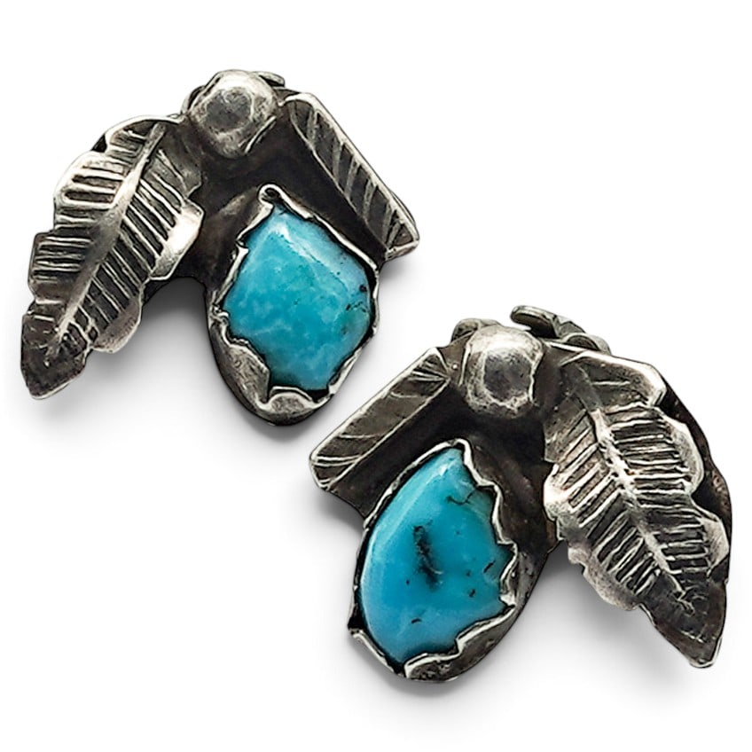 A Pair Of Navajo Silver And Turquoise Leaf Clip Earrings: A pair of Navajo silver and turquoise leaf clip earrings Late 20th century Unmarked. Tested sterling silver. Each with a bezel-set turquoise cabochon accented by applied silver leaf motifs and silver 