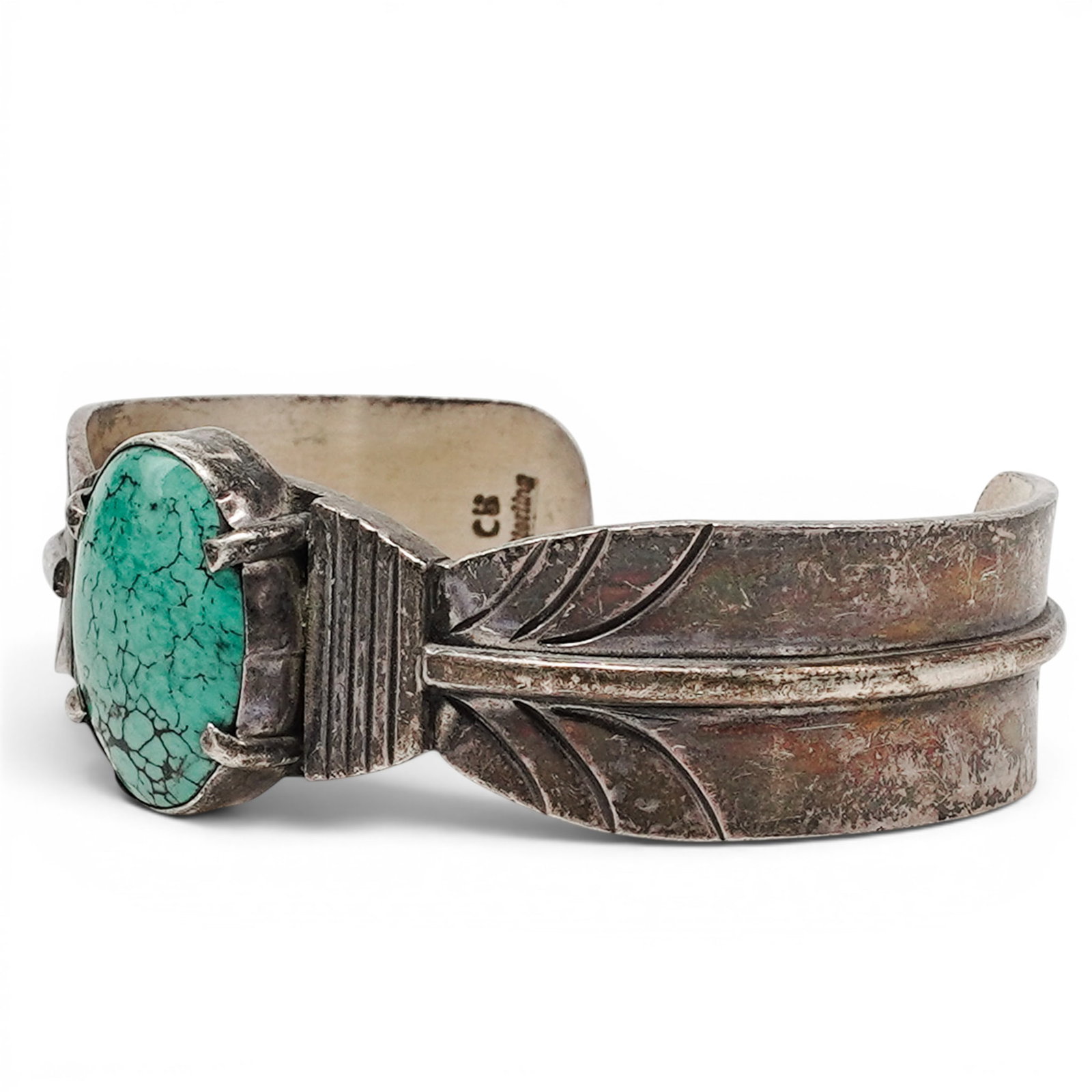 A Cynthia Begay Navajo Sterling Silver And Turquoise Feather Form Cuff Bracelet: A Cynthia Begay Navajo sterling silver and turquoise feather form cuff bracelet Late 20th Century Stamped: C.B. / Sterling. A cuff bracelet with an oval turquoise cabochon in a bezel setting, flanked 