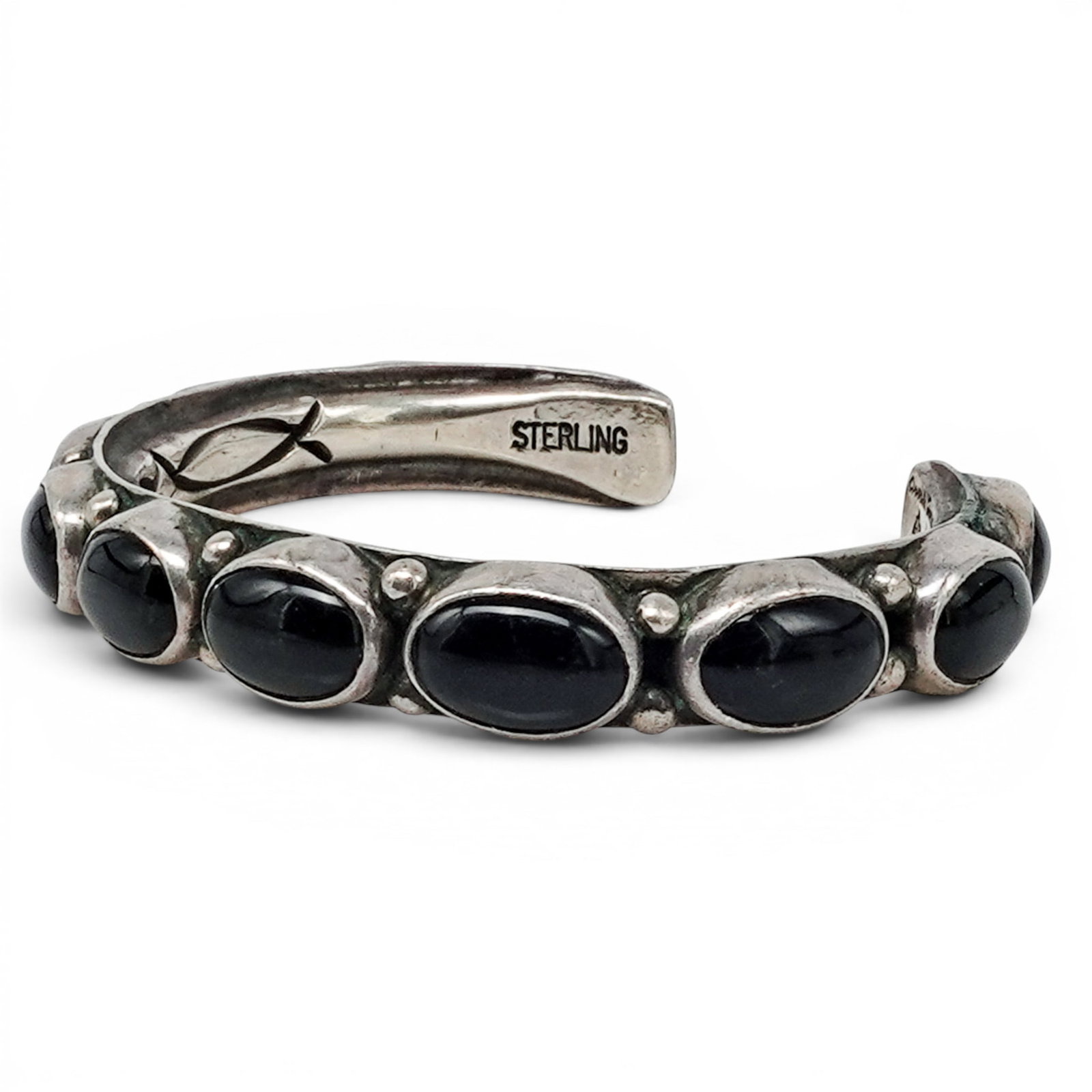 An Orville Z. Tsinnie Navajo Sterling Silver And Onyx Cuff Bracelet: An Orville Z. Tsinnie Navajo sterling silver and onyx cuff bracelet Late 20th century Stamped: Orville Z. Tsinnie of New Mexico / Sterling A tapering sterling silver cuff bracelet with multiple oval b