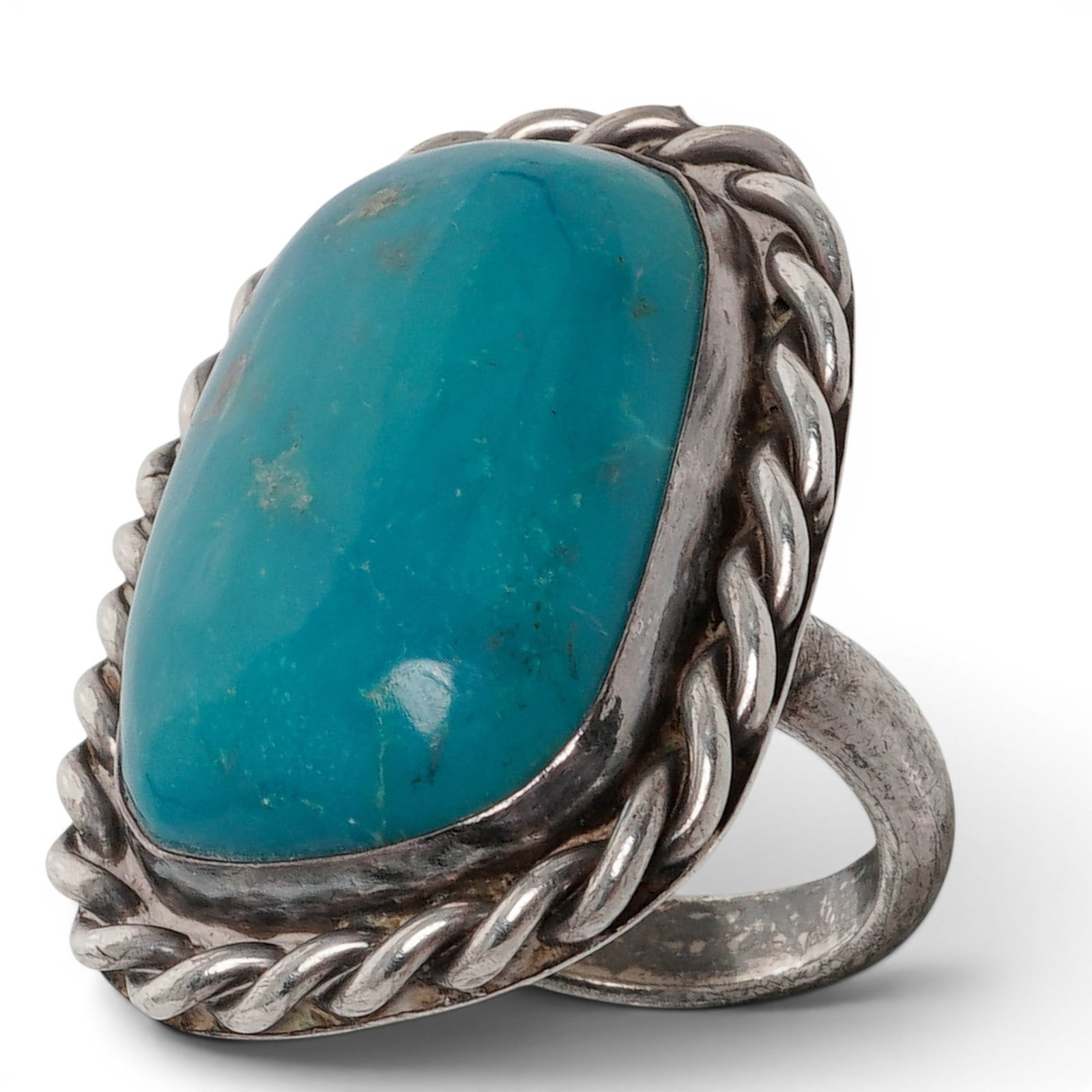 A Navajo Sterling Silver And Turquoise Ring: A Navajo sterling silver and turquoise ring Late 20th century Stamped: Unverified A.R. mark / Sterling. A substantial ring set with a large oval turquoise cabochon in a bezel mount, framed by a heavy 