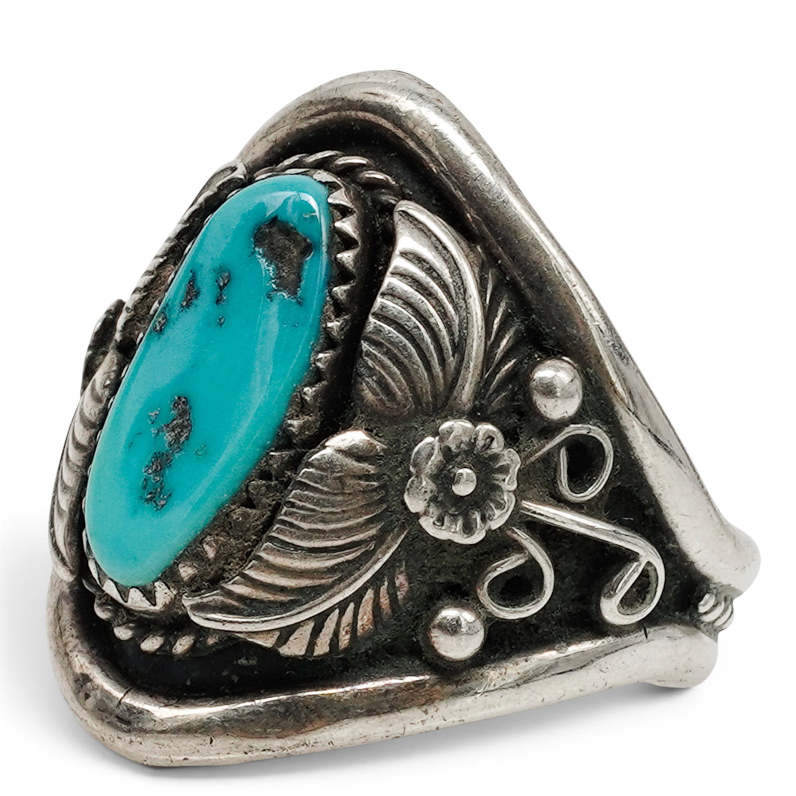 A Richard Begay Navajo Sterling Silver And Turquoise Ring: A Richard Begay Navajo sterling silver and turquoise ring Late 20th century Stamped: R.B. / Sterling. An oval turquoise cabochon in a serrated bezel mount, accented with applied leaves, fan motifs, tw