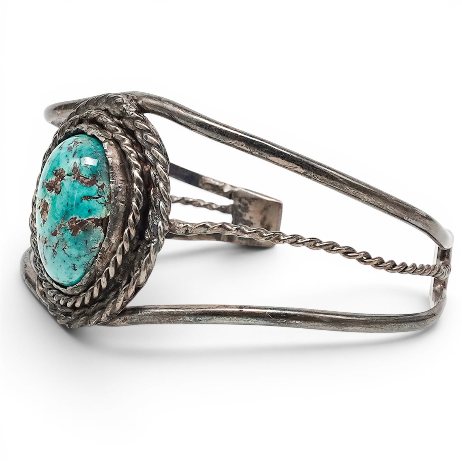 A Navajo Sterling Silver And Turquoise Wirework Cuff Bracelet: A Navajo sterling silver and turquoise wirework cuff bracelet Late 20th century Unmarked. Tested sterling silver. A cuff bracelet with a central oval bezel set turquoise stone surrounded by twisted wi