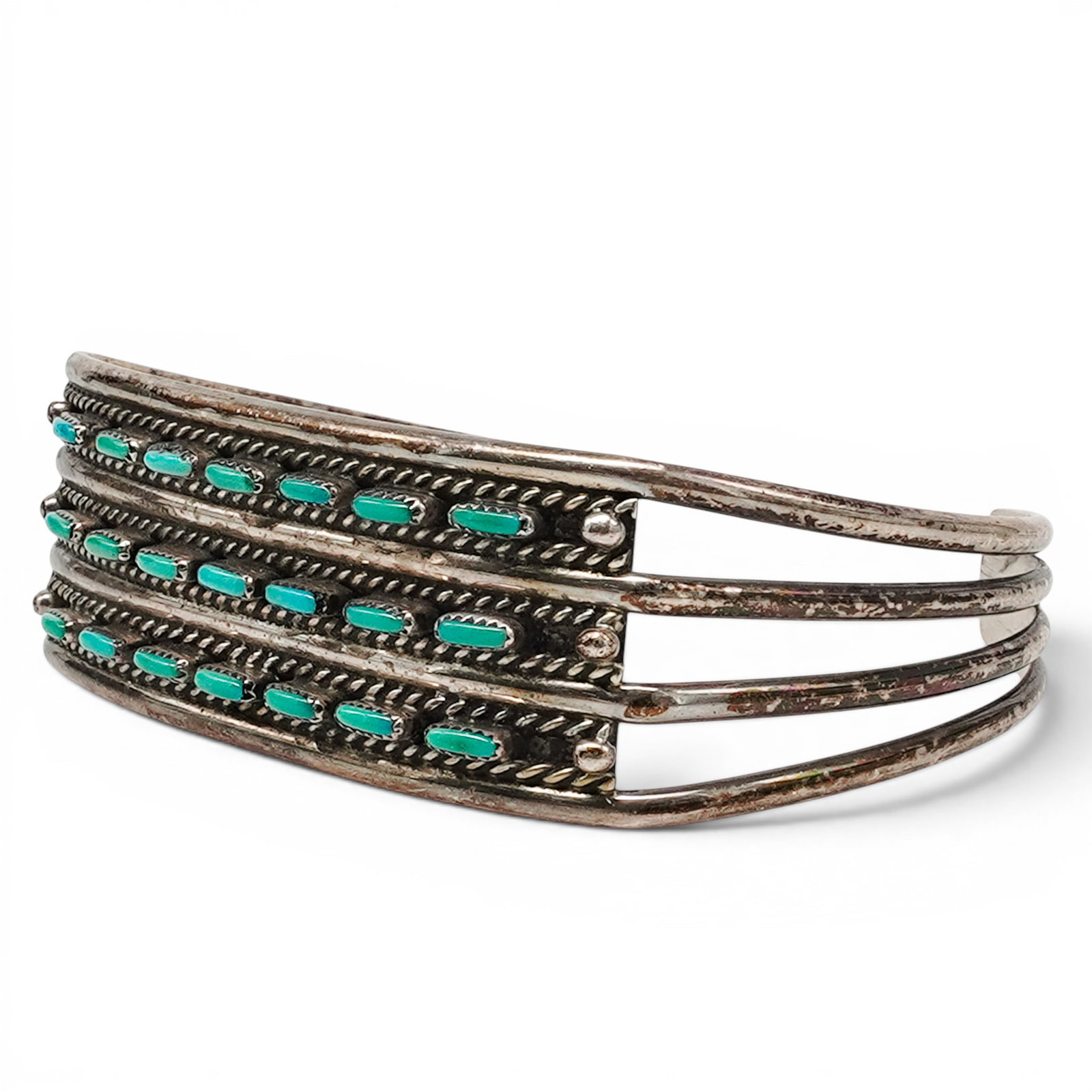 A Navajo Sterling Silver And Turquoise Row Cuff Bracelet: A Navajo sterling silver and turquoise row cuff bracelet Late 20th century Unmarked. Tested sterling silver. A narrow cuff bracelet with four rows of channel set turquoise stones separated by twisted 