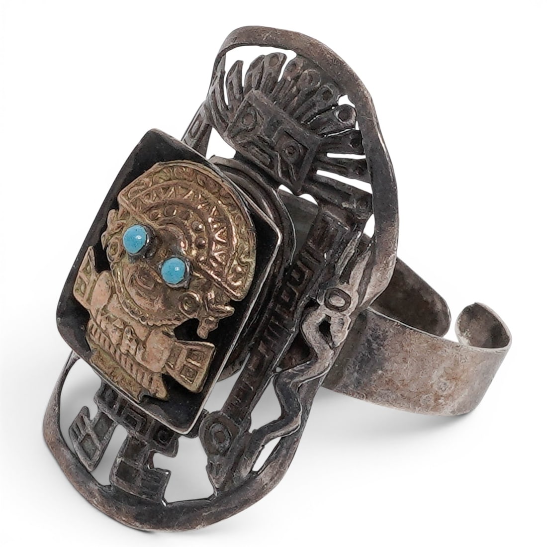 A Peruvian Sterling Silver, 18K Gold, And Turquoise Warrior Tumi Ring: A Peruvian sterling silver, 18k gold, and turquoise warrior tumi ring Late 20th century Stamped: 18K / .925. A figural ring depicting a pre-Columbian style tumi warrior in 18k gold with turquoise-set 