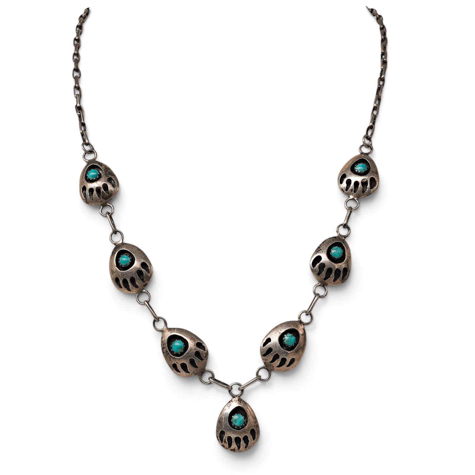A Navajo Sterling Silver And Turquoise Bear Paw Link Necklace: A Navajo sterling silver and turquoise bear paw link necklace Late 20th Century Stamped: Sterling. A necklace with seven bear paw-form links, each centered by a bezel-set turquoise cabochon, connected