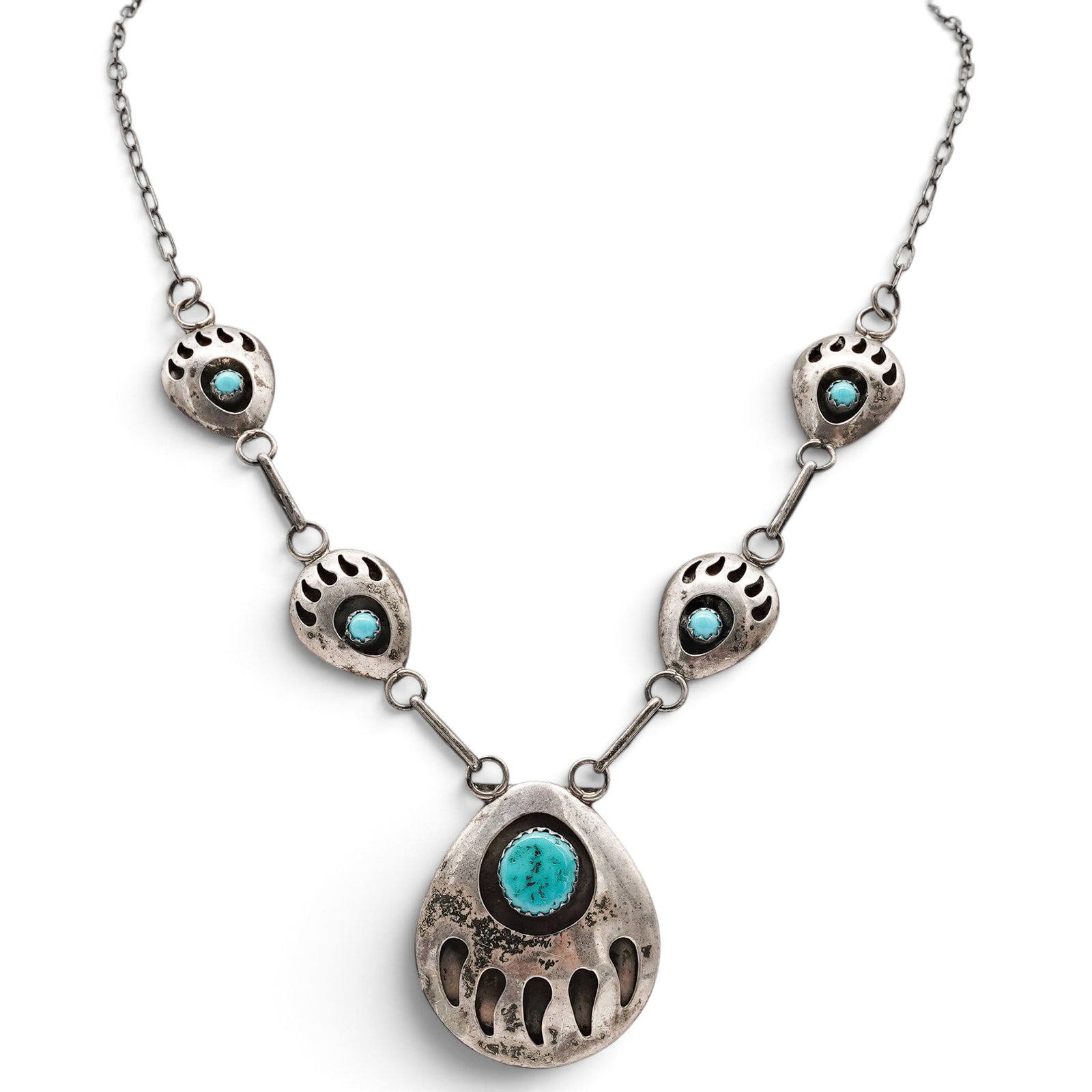 A Selina Jake Navajo Silver And Turquoise Bear Paw Link Necklace: A Selina Jake Navajo silver and turquoise bear paw link necklace Late 20th century Stamped: S.J. / Sterling. A necklace with four bear paw-form links each centered by a bezel-set turquoise cabochon, s