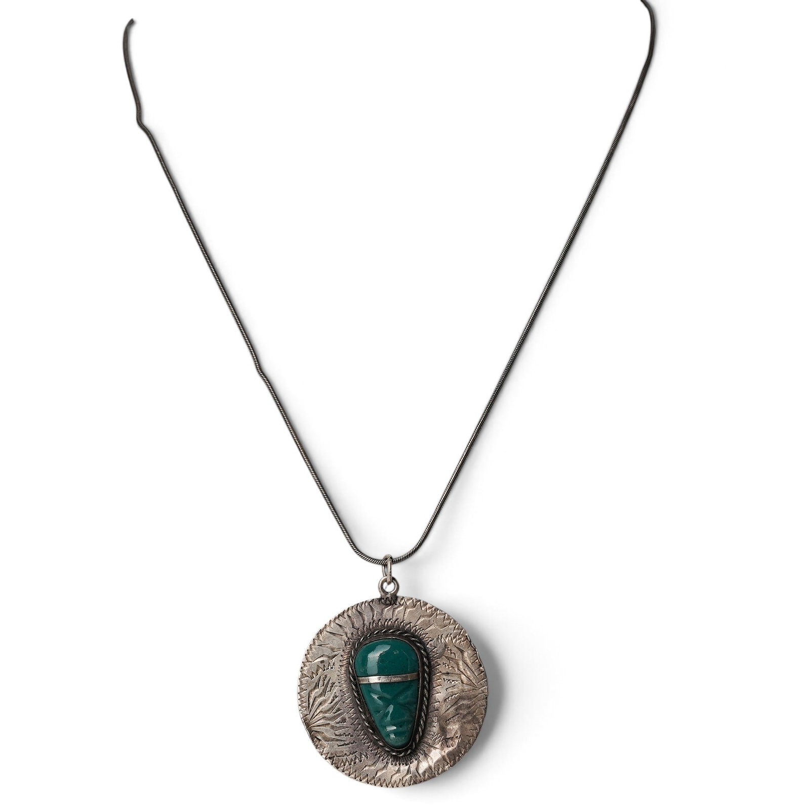A Mexican Sterling Silver And Turquoise Aztec Calendar Pendant Necklace: A Mexican sterling silver and turquoise Aztec calendar pendant necklace Late 20th century Unmarked. Tested sterling silver. A circular pendant with engraved Aztec calendar motifs centered by an oval t