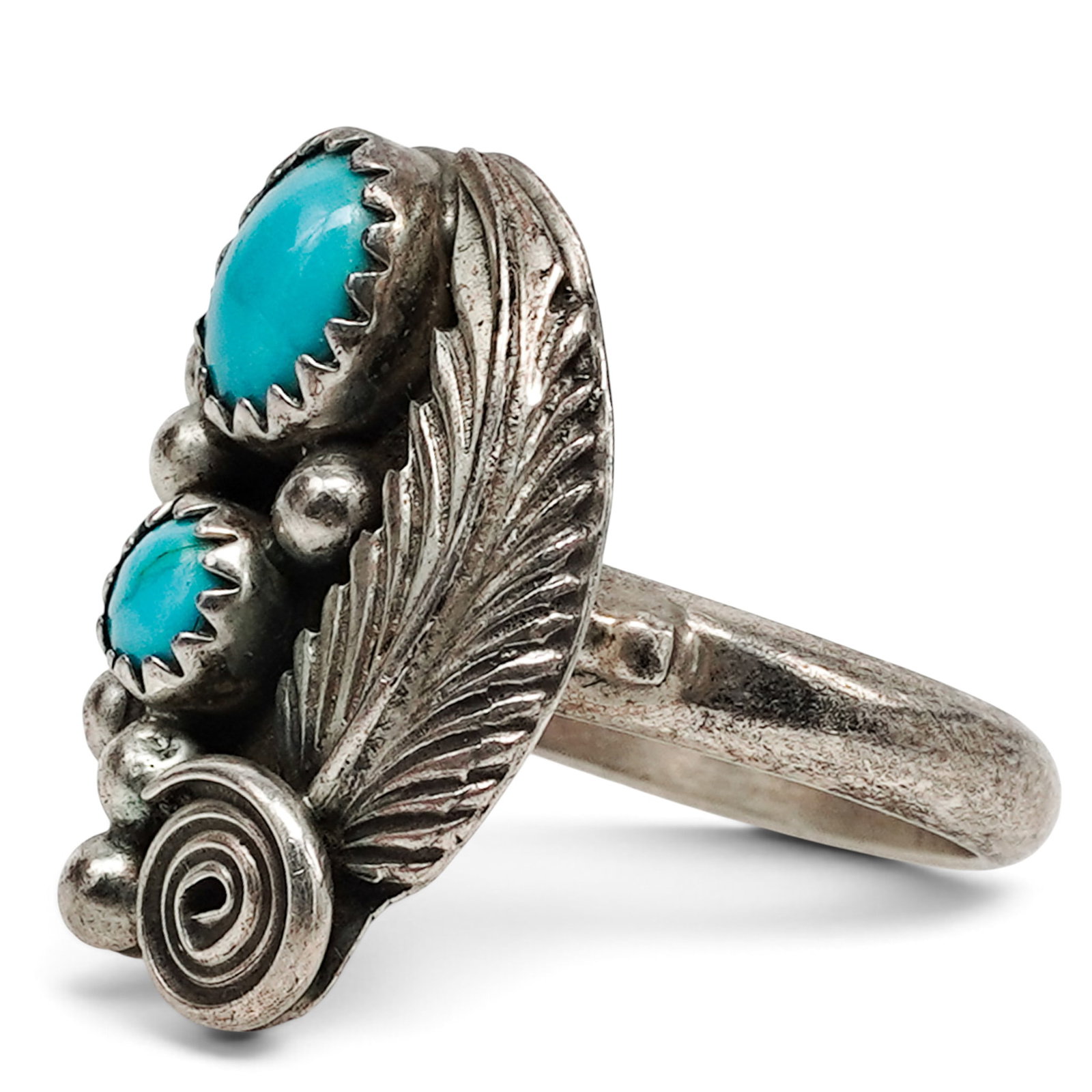A Navajo Sterling Silver And Turquoise Foliate Scrollwork Ring: A Navajo sterling silver and turquoise foliate scrollwork ring Late 20th century Stamped: M.Y., unidentified maker / Sterling. A ring with two oval turquoise cabochons in serrated bezels, accented by 
