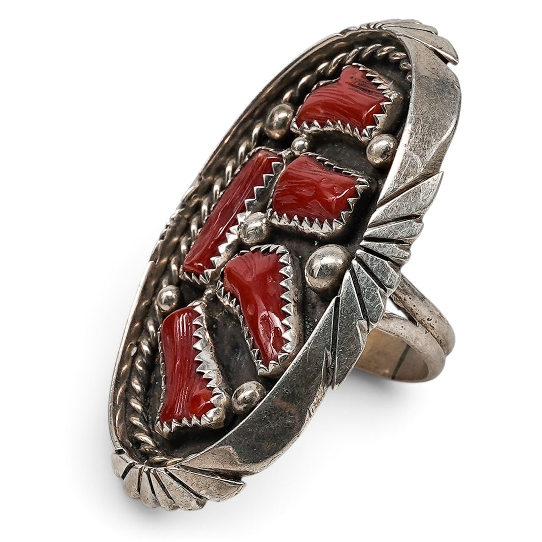 A Mathilda Benally Navajo Sterling Silver And Coral Cluster Ring: A Mathilda Benally Navajo sterling silver and coral cluster ring Late 20th century Stamped: M.B. / Sterling. An elongated ring with five bezel-set coral cabochons in a graduated cluster arrangement, w