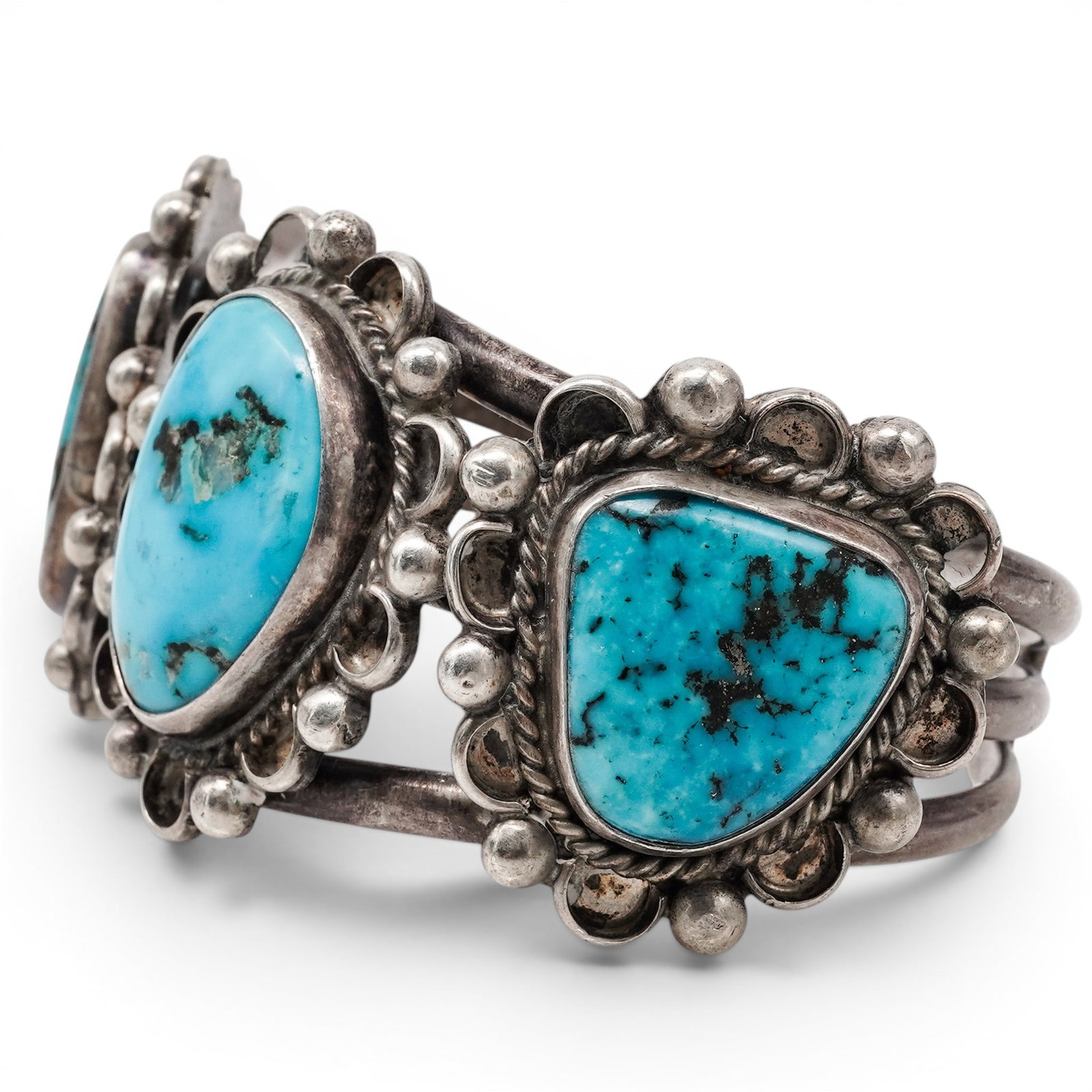 A Navajo Sterling Silver And Turquoise Three Stone Cuff Bracelet: A Navajo sterling silver and turquoise three stone cuff bracelet Late 20th century Stamped : L.E.O., unidentified signature. Tested sterling silver. A heavy three wire cuff bracelet set with three lar