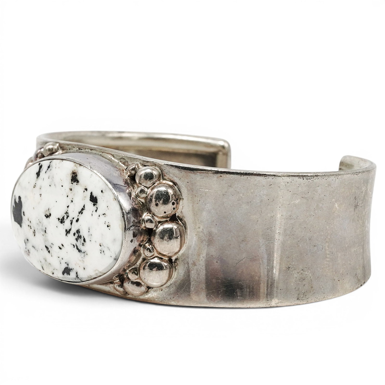 A Nelson Garcia Kewa Sterling Silver And White Buffalo Cuff Bracelet: A Nelson Garcia Kewa sterling silver and white buffalo cuff bracelet Late 20th Century Stamped: N.G. / Sterling. A wide tapered cuff bracelet centered by a large oval white buffalo cabochon in a serra
