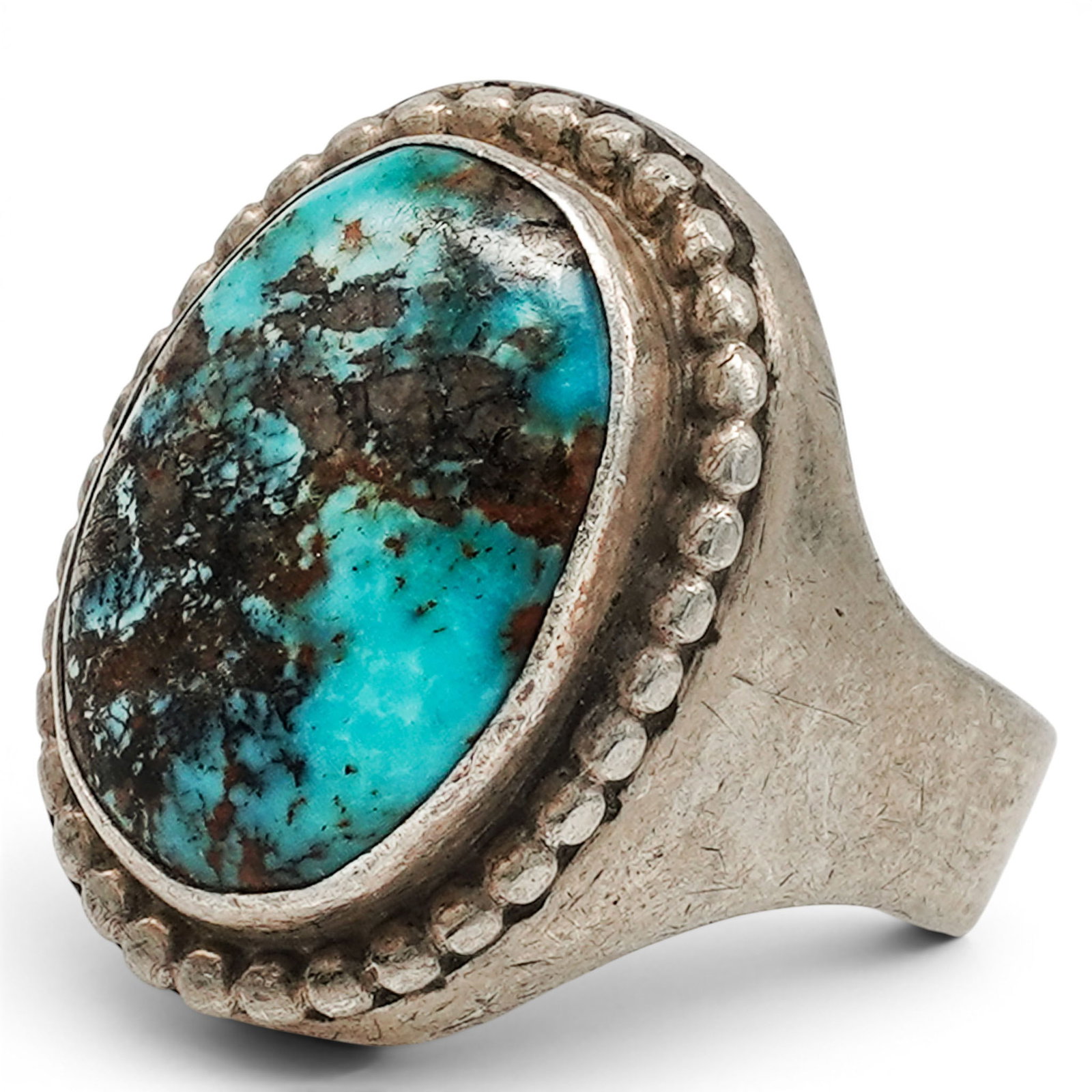 A Mexican Sterling Silver And Turquoise Ring: A Mexican sterling silver and turquoise ring Late 20th century Stamped: Silver / Made in Mexico A large oval turquoise cabochon in a serrated bezel mount, framed by a beaded border on a substantial si