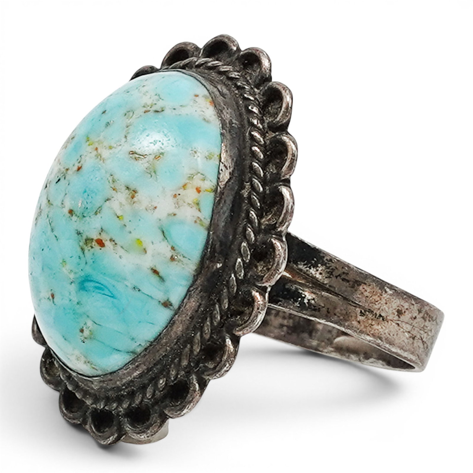 A Navajo Sterling Silver And Turquoise Ring: A Navajo sterling silver and turquoise ring Late 20th century Stamped: Sterling. An oval turquoise cabochon in a bezel mount, surrounded by scalloped wirework and mounted on a split shank band with st