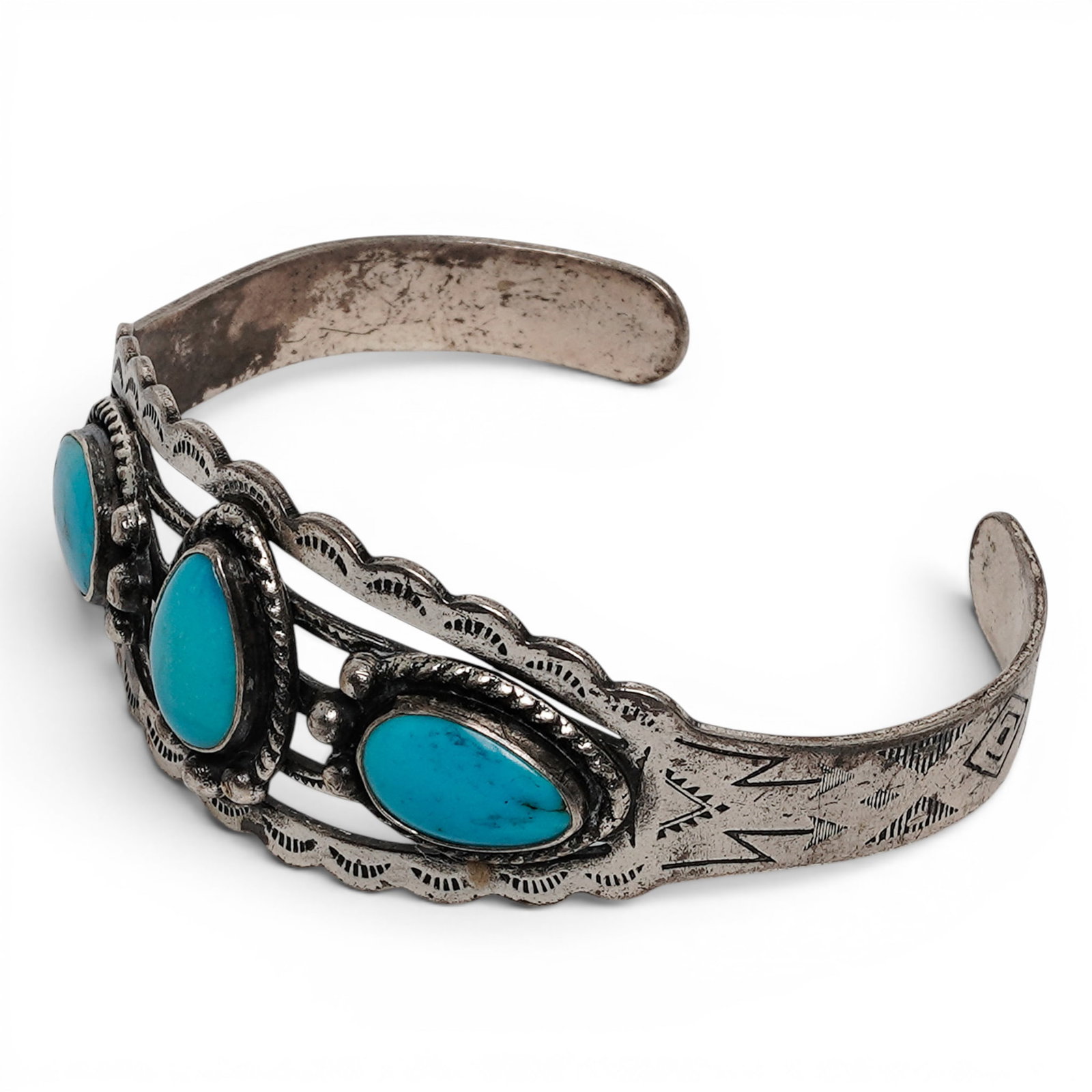 A Navajo Sterling Silver And Turquoise Three Stone Cuff Bracelet: A Navajo sterling silver and turquoise three stone cuff bracelet Late 20th century Stamped: Sterling / unidentified pictographic mark. A tapered cuff bracelet set with three oval turquoise cabochons i