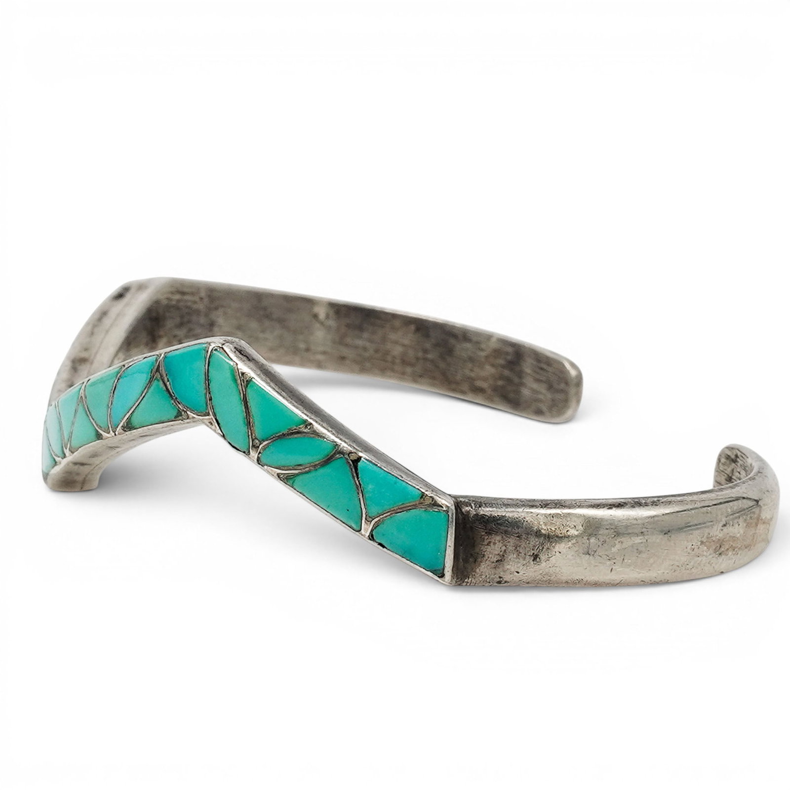 A Sibert And Janita Kallestewa Zuni Sterling Silver And Turquoise Geometric Inlay Cuff Bracelet: A Sibert and Janita Kallestewa Zuni sterling silver and turquoise geometric inlay cuff bracelet Late 20th Century Stamped: S.K.J. / Sterling. A narrow silver cuff bracelet with continuous geometric tu