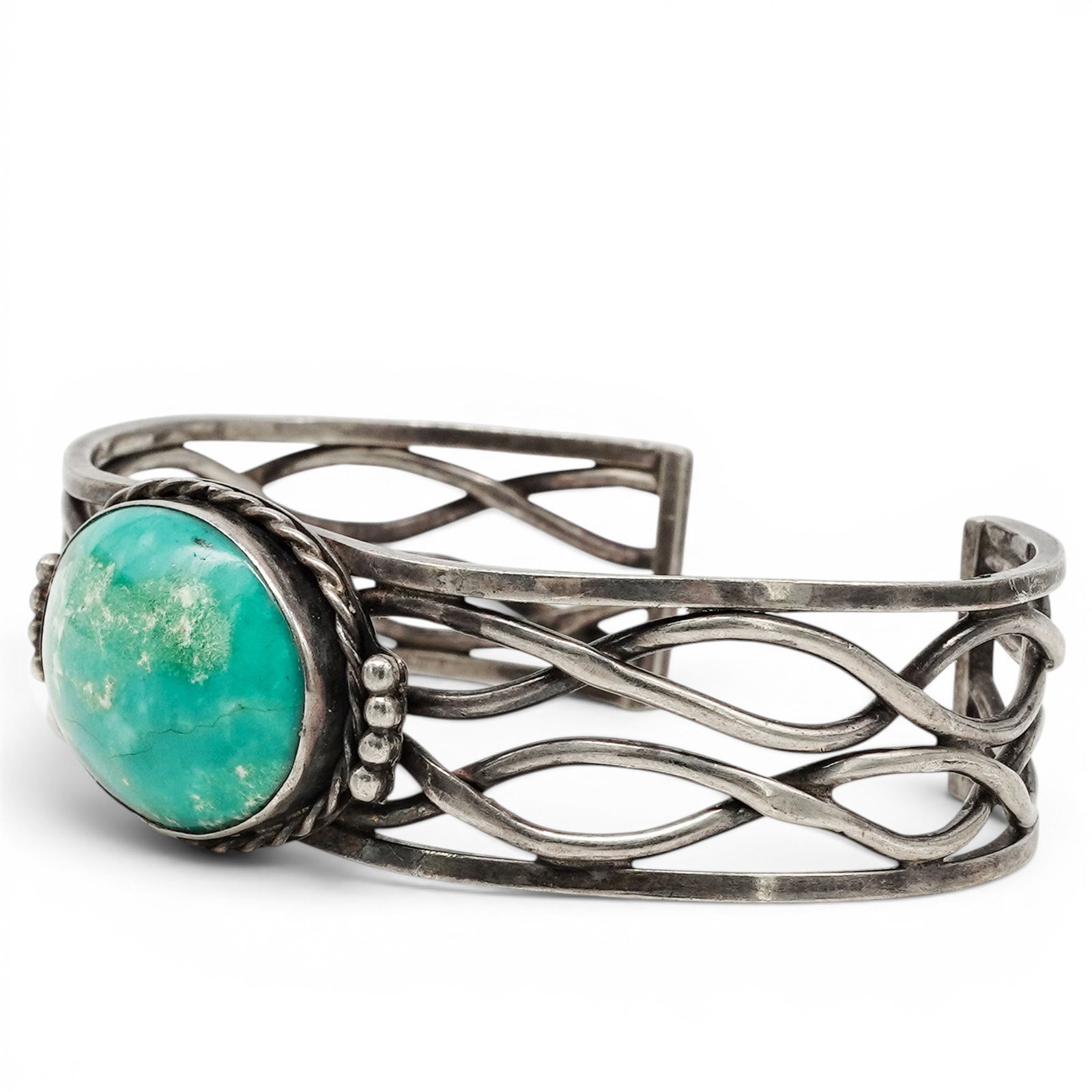 A Navajo Sterling Silver And Turquoise Openwork Wire Cuff Bracelet: A Navajo sterling silver and turquoise openwork wire cuff bracelet Late 20th century Unmarked. Tested sterling silver. A wide openwork cuff bracelet with flowing wirework construction centered by an o