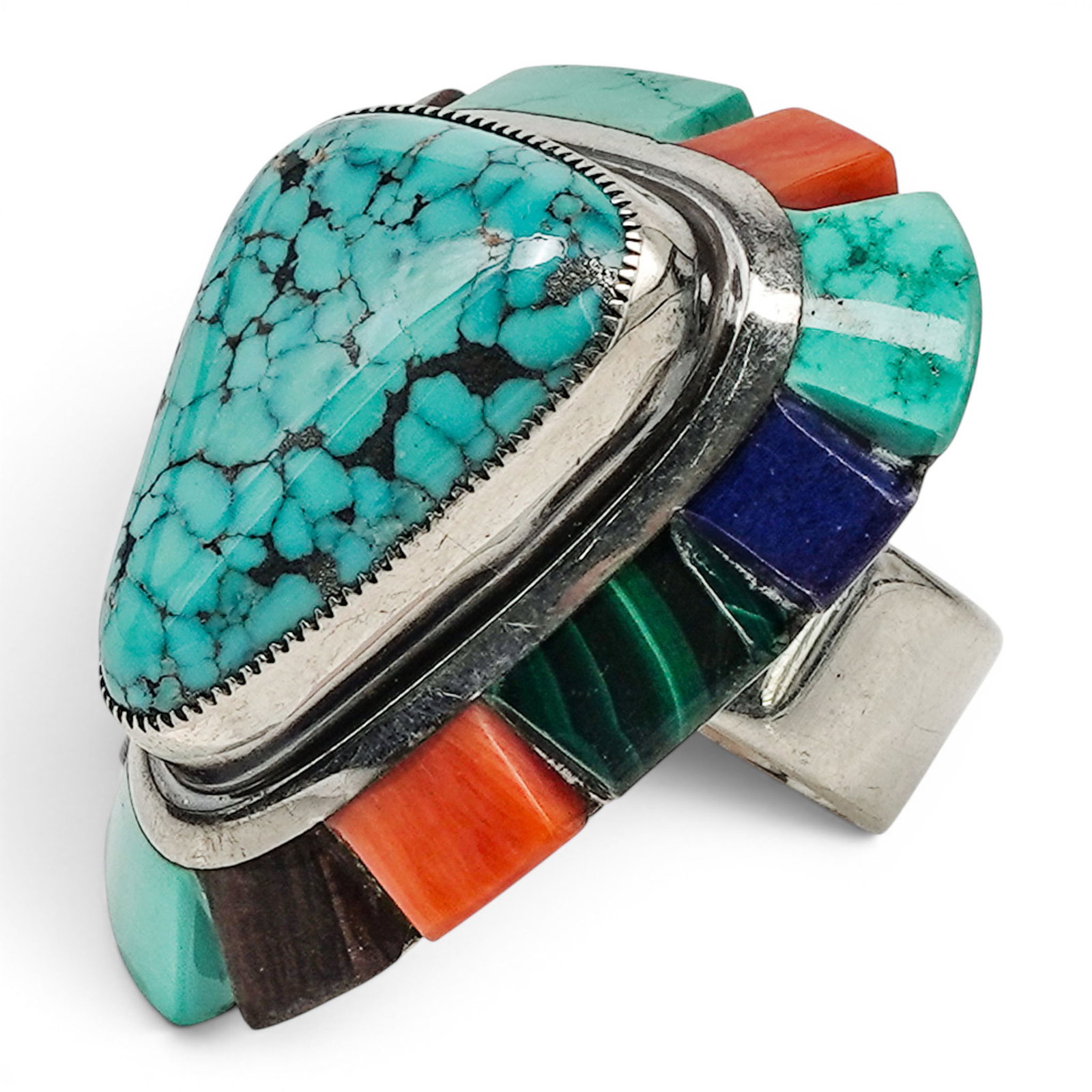 A Saunsa Navajo Sterling Silver And Multistone Ring: A Saunsa Navajo sterling silver and multistone ring Late 20th century Stamped: Saunsa. Tested sterling silver. A large statement ring centered by a triangular turquoise cabochon in a serrated bezel mo