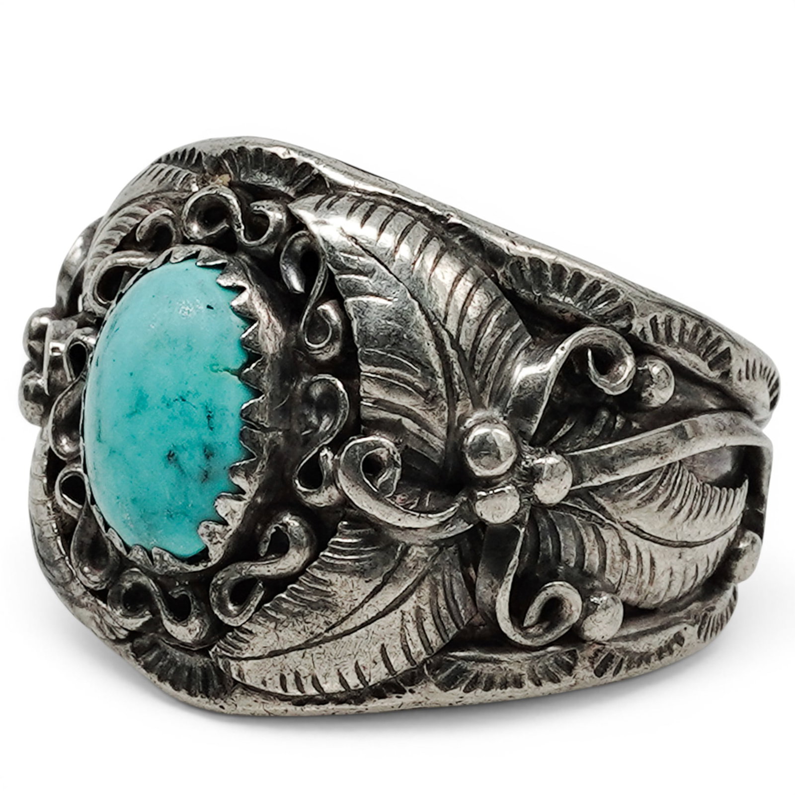 A John Chavez Navajo Sterling Silver And Turquoise Ring: A John Chavez Navajo sterling silver and turquoise ring Late 20th century Stamped: J.J. / Sterling An oval turquoise cabochon in a bezel mount, surrounded by applied scrollwork, beadwork, and leaf mot