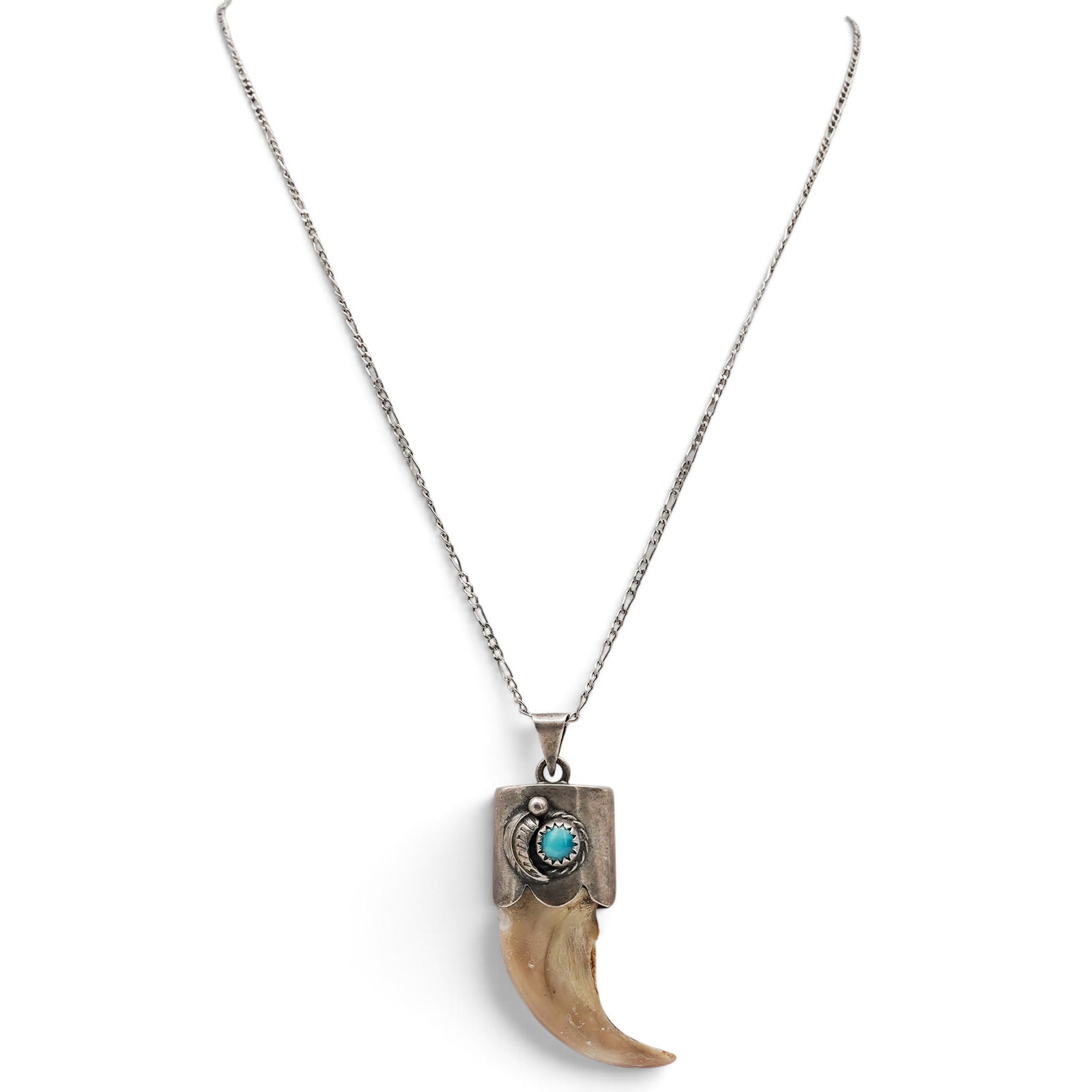 A Navajo Sterling Silver, Turquoise, And Claw Pendant Necklace: A Navajo sterling silver, turquoise, and claw pendant necklace Late 20th century Unmarked. Tested sterling silver. A necklace suspending a polished claw pendant mounted in a silver cap accented by a