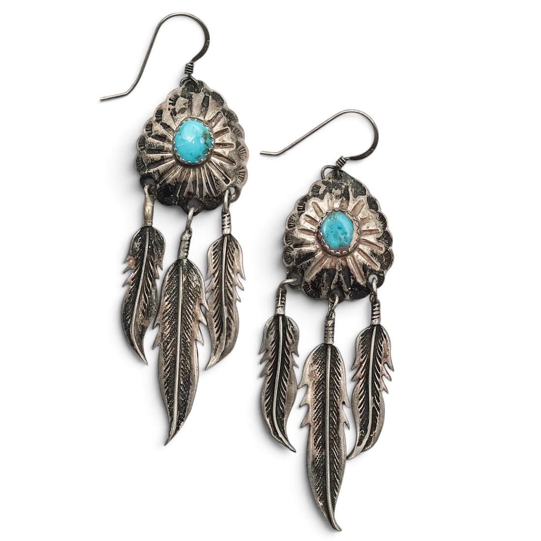 A Pair Of Navajo Sterling Silver And Turquoise Feather Fringe Earrings: A pair of Navajo sterling silver and turquoise feather fringe earrings Late 20th century Unmarked Tests for sterling. Each stamped oval earring is set with an oval turquoise cabochon in a serrated bez