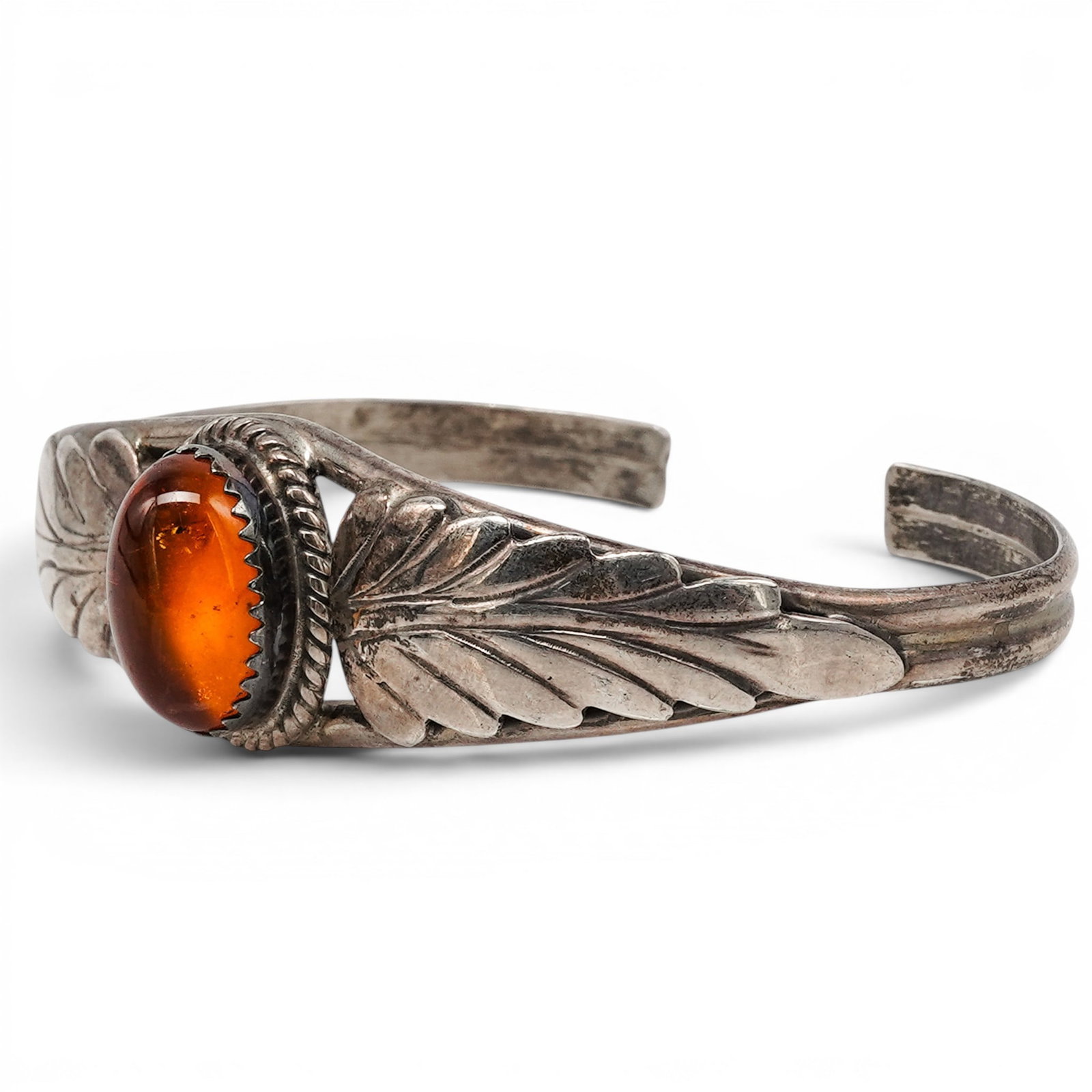 A Harry Spencer Navajo Sterling Silver And Amber Leaf Motif Cuff Bracelet: A Harry Spencer Navajo sterling silver and amber leaf motif cuff bracelet Late 20th century Stamped: H. Spencer / Sterling. A tapered cuff bracelet centered by an oval amber cabochon in a beaded bezel