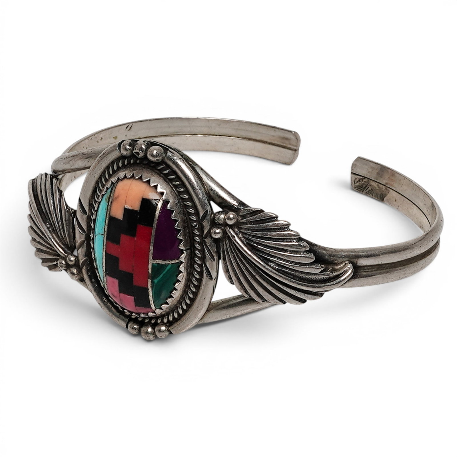 A Zuni Sterling Silver And Multistone Inlay Fan Motif Cuff Bracelet: A Zuni sterling silver and multistone inlay fan motif cuff bracelet Late 20th century Stamped: .925. A tapered cuff bracelet centered by a circular mosaic inlay panel comprising of malachite,