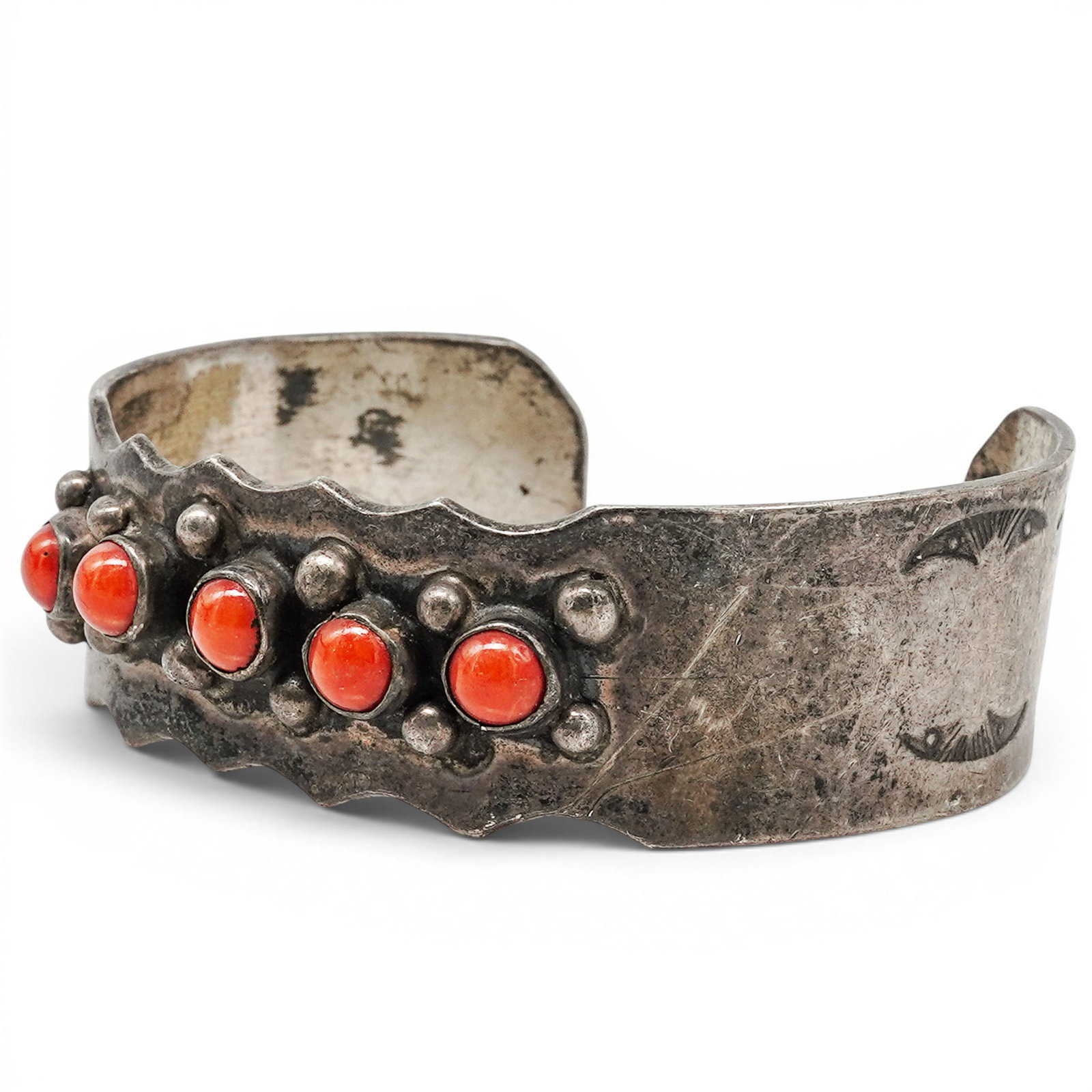 A Navajo Sterling Silver And Coral Row Cuff Bracelet: A Navajo sterling silver and coral row cuff bracelet Late 20th century Unmarked. Tested sterling silver. A tapered cuff bracelet set with a graduated row of coral cabochons in bezel mounts, accented