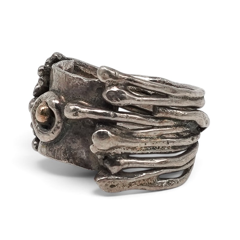A Modernist Sterling Silver And Gold Sculptural Ring: A modernist sterling silver and gold sculptural ring Late 20th century Unmarked. Tested sterling silver. A sculptural ring with layered silverwork and an applied gold central accent, featuring raindro